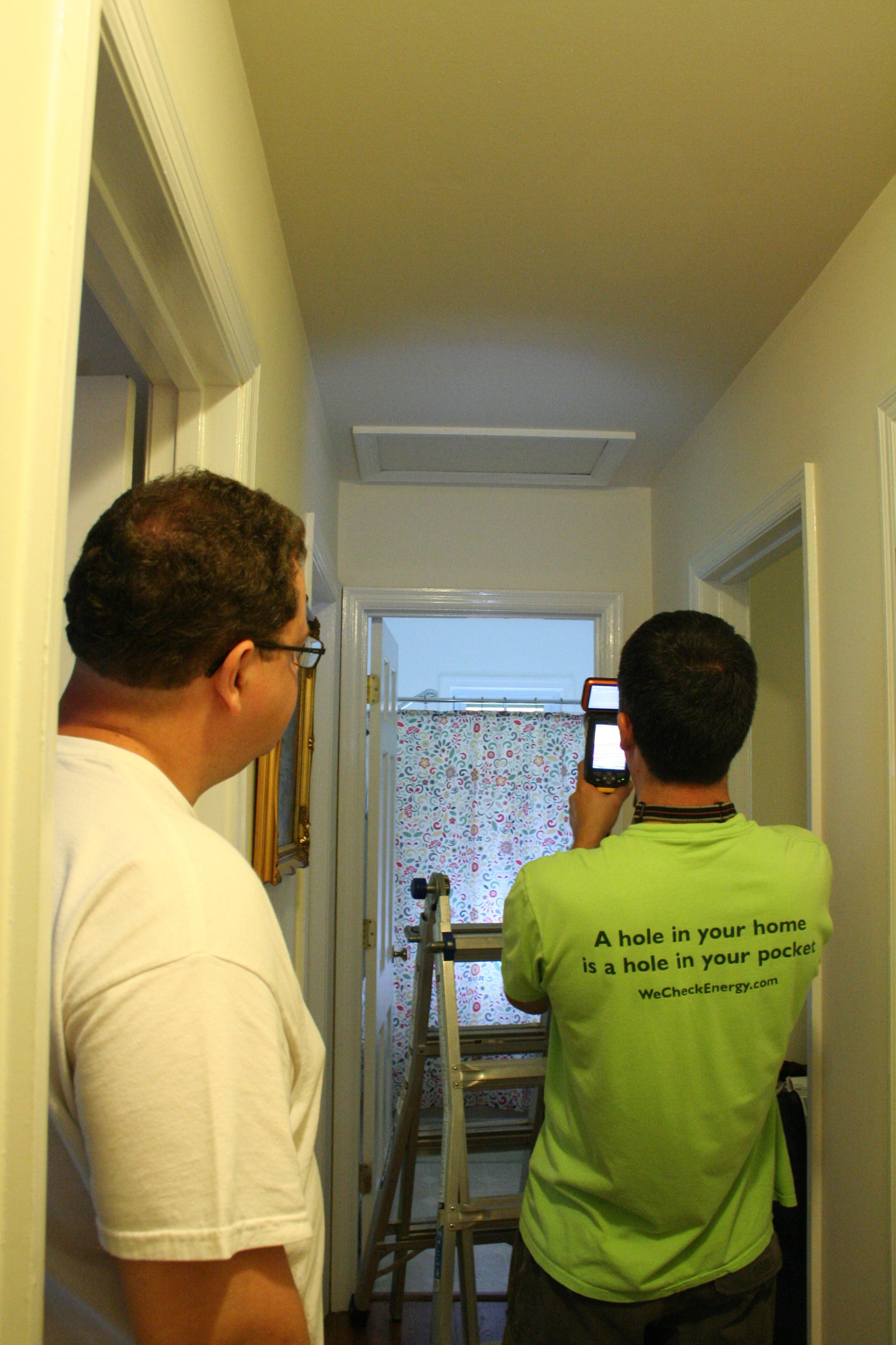 Energy auditor using an infrared camera to detect and highlight air leaks around a window, helping homeowners identify energy loss and improve home efficiency