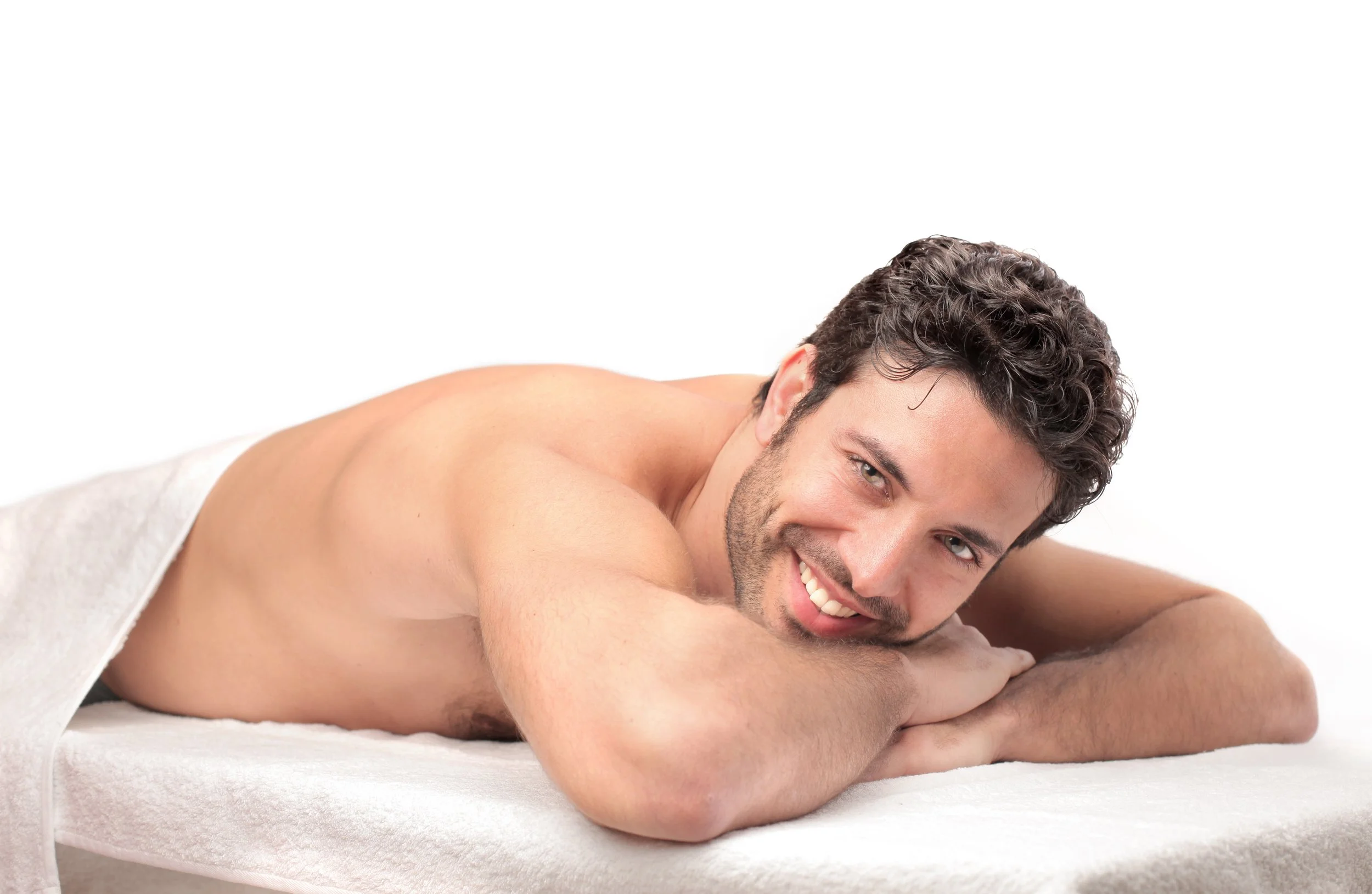 Ein Mann liegt entspannt auf einer Massagebank, lächelnd, während er massiert wird.