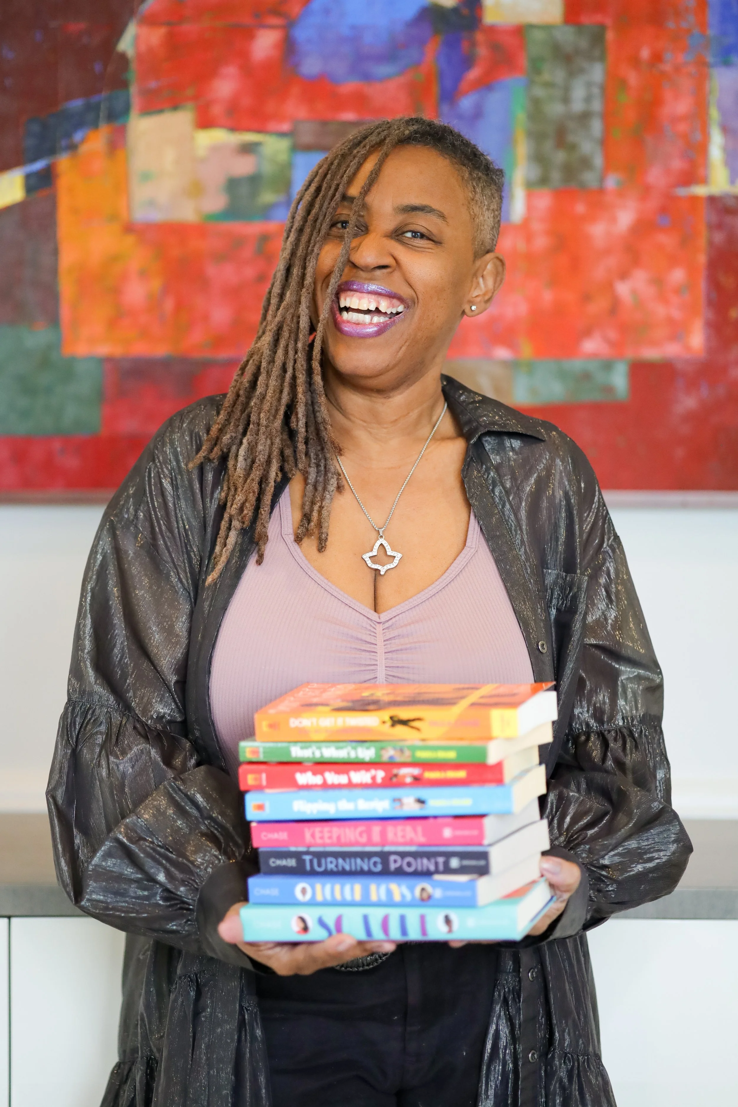 Black woman with locs holding colorful books