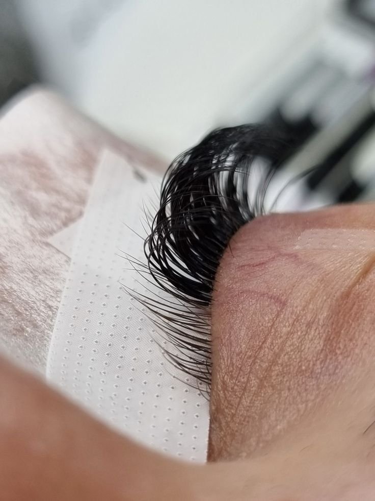 Nahaufnahme von künstlichen Wimpern, die auf eine Hautseite geklebt sind.