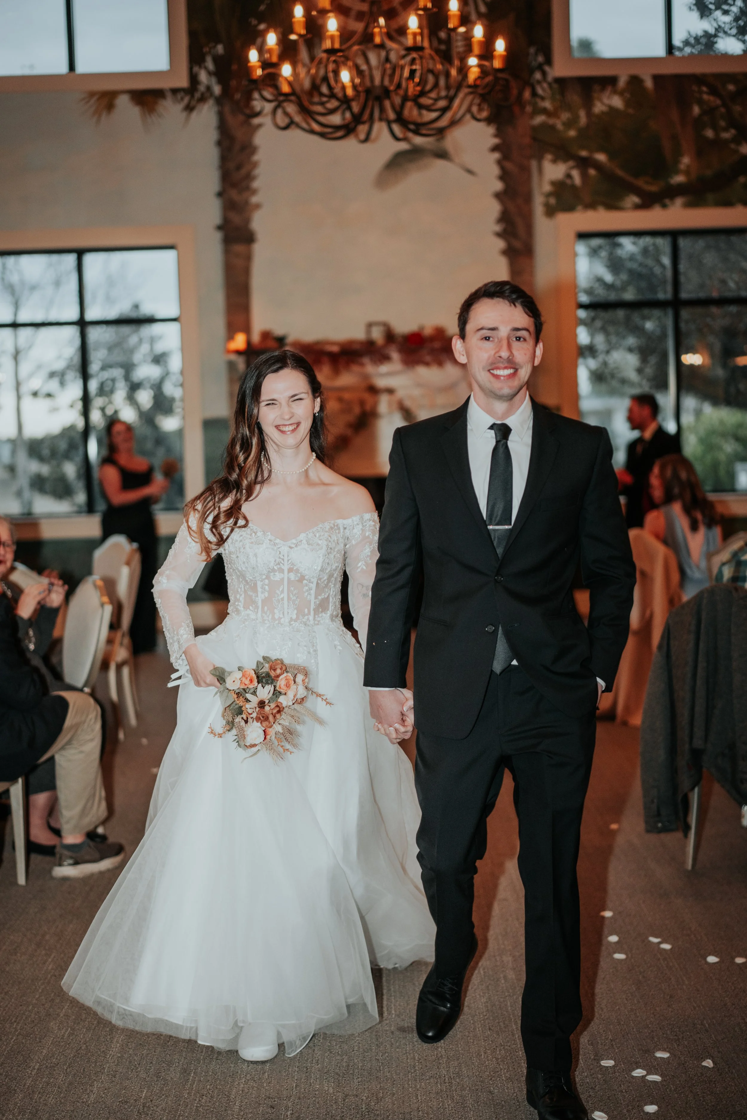 Bride and groom walk hand in hand down the aisle, smiling joyfully after their ceremony surrounded by loved ones — planned by Charlotte Wedding Planner at Lowcountry Park Venues.