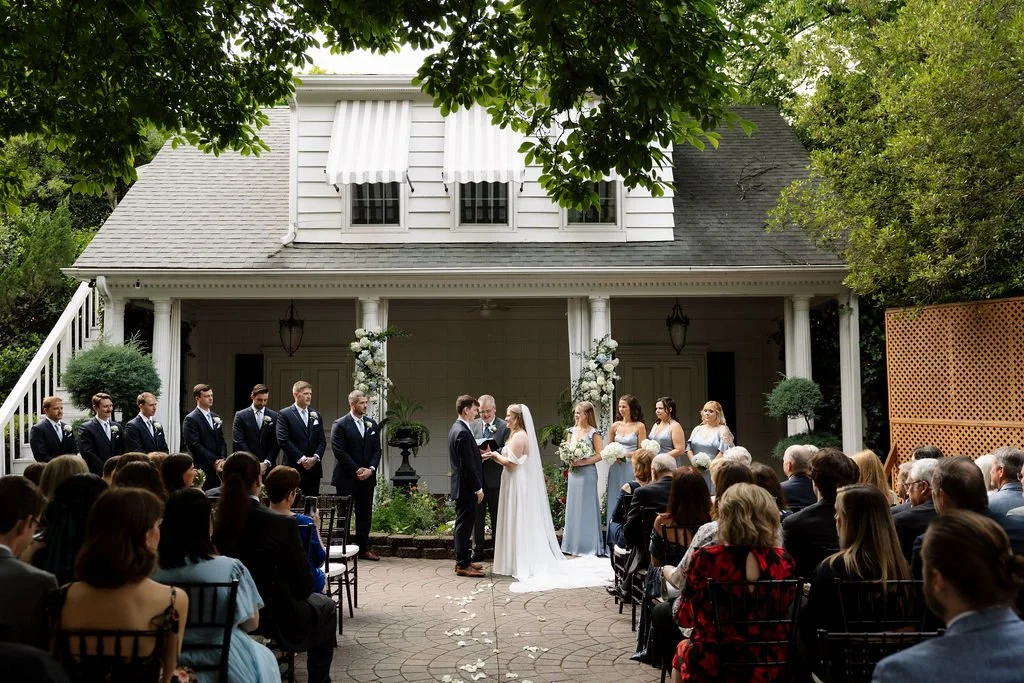 An intimate outdoor ceremony at a home with guests seated outdoors.