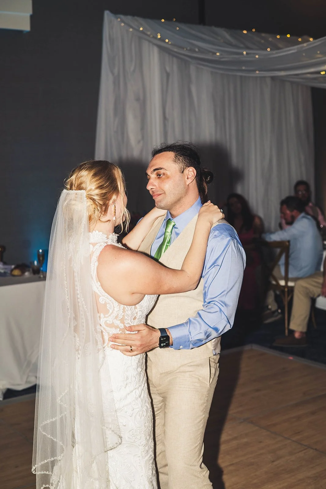 Bride and groom share their first dance surrounded by loved ones, illuminated by soft lighting and romantic drapery — planned by Charlotte Wedding Planner at Courtyard by Marriott Carolina Beach Oceanfront.