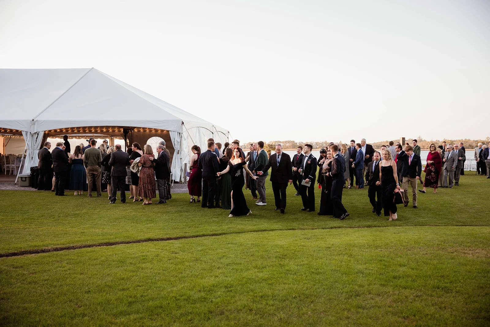 Guests walking towards a large wedding tent set up on a grassy outdoor venue.