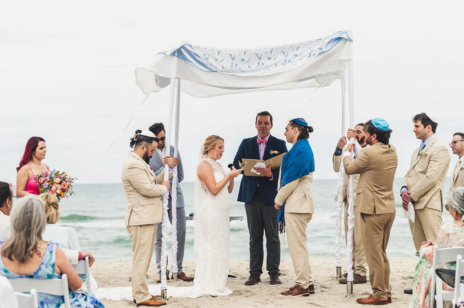 Beachfront ceremony under a white canopy with the couple exchanging vows as waves crash gently behind them — planned by Charlotte Wedding Planner.