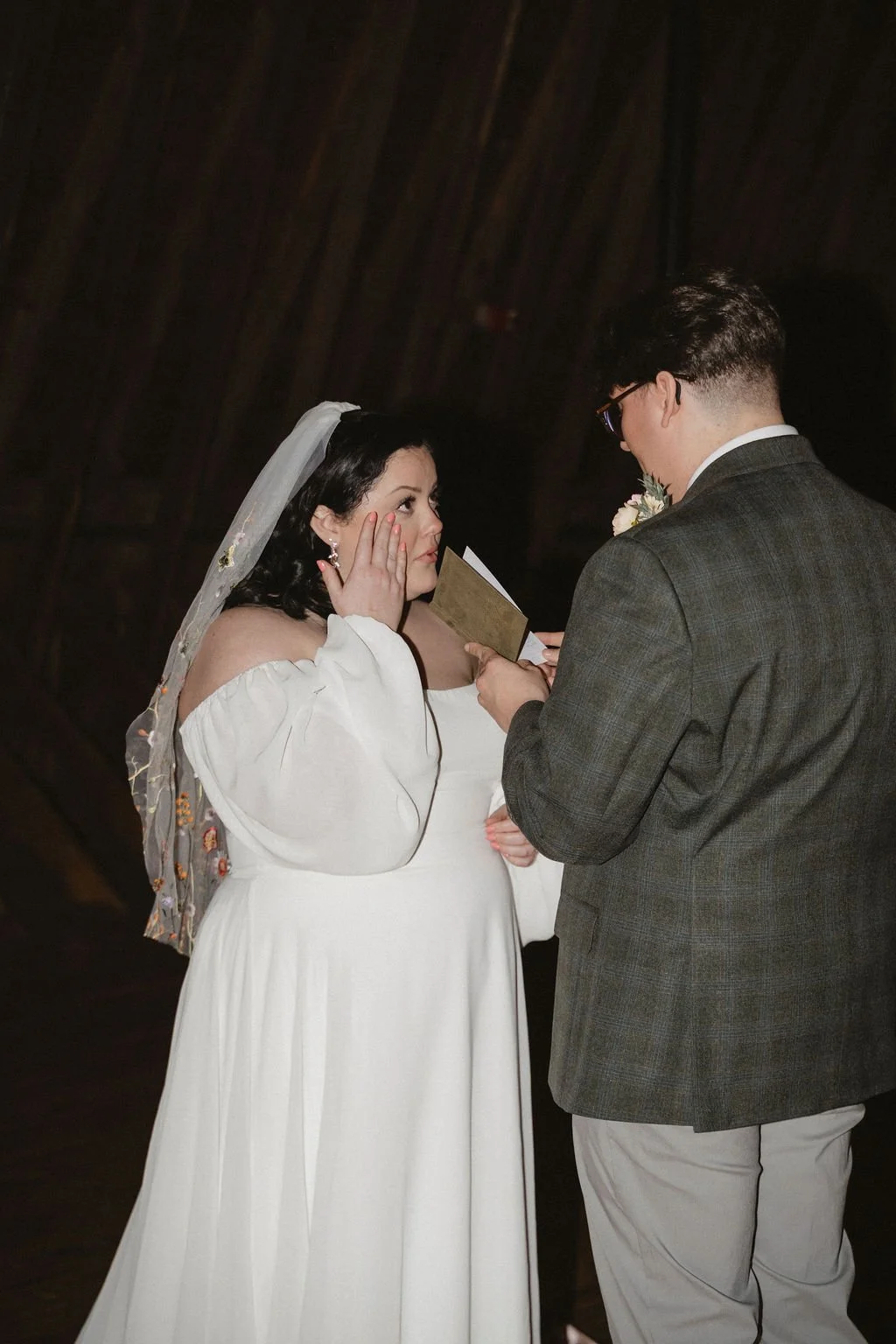 Bride wipes away tears as the groom reads heartfelt vows during an intimate ceremony in a cozy barn venue — coordinated by Charlotte Wedding Coordinator at Anne Springs Close Greenway.