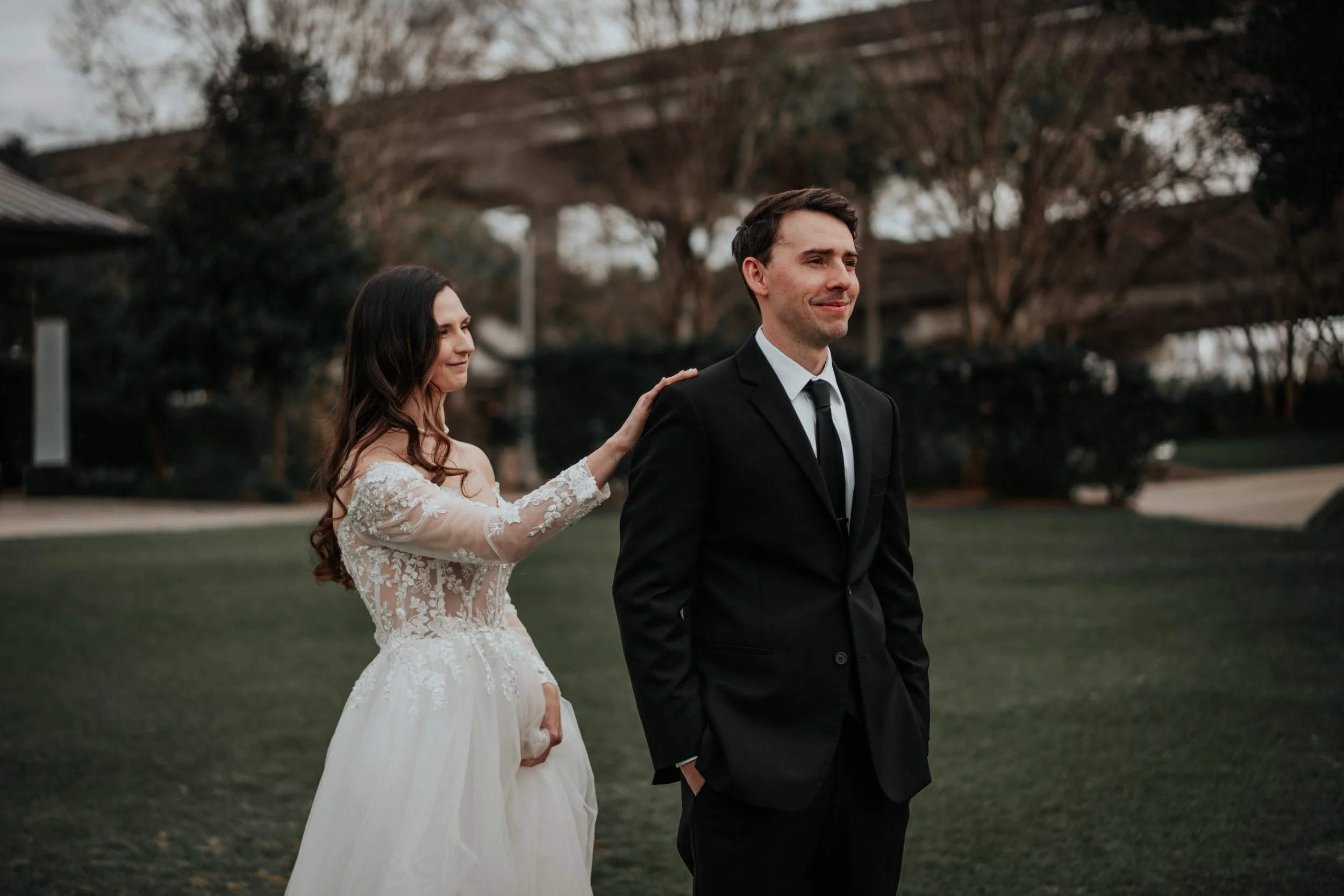 Bride taps groom’s shoulder for their first look in the gardens at Lowcountry Park Venues — planned by Charlotte Wedding Planner.