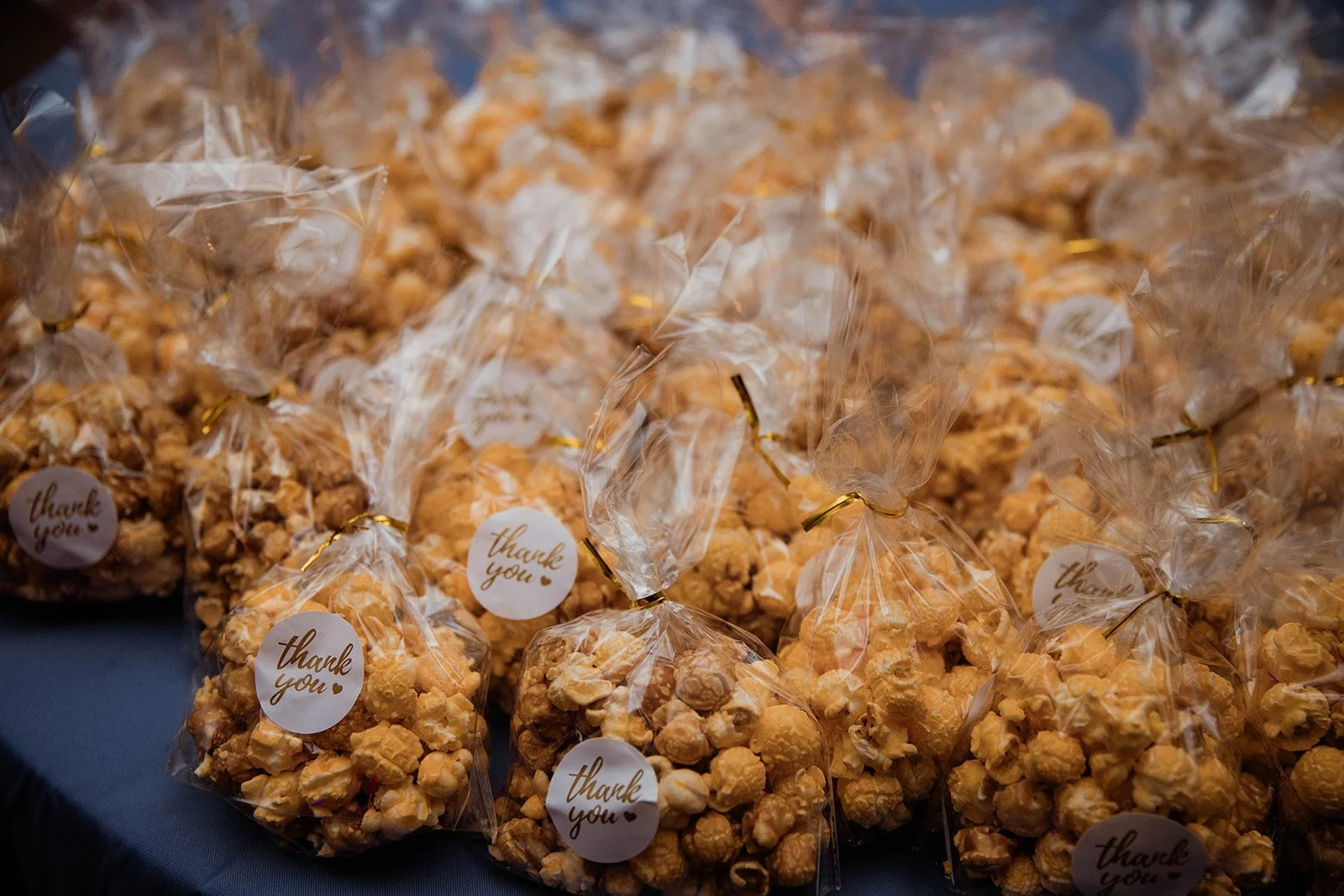 Wedding favors of caramel popcorn neatly packed in clear bags with “thank you” stickers, ready for guests to enjoy — planned by Charlotte Wedding Planner.