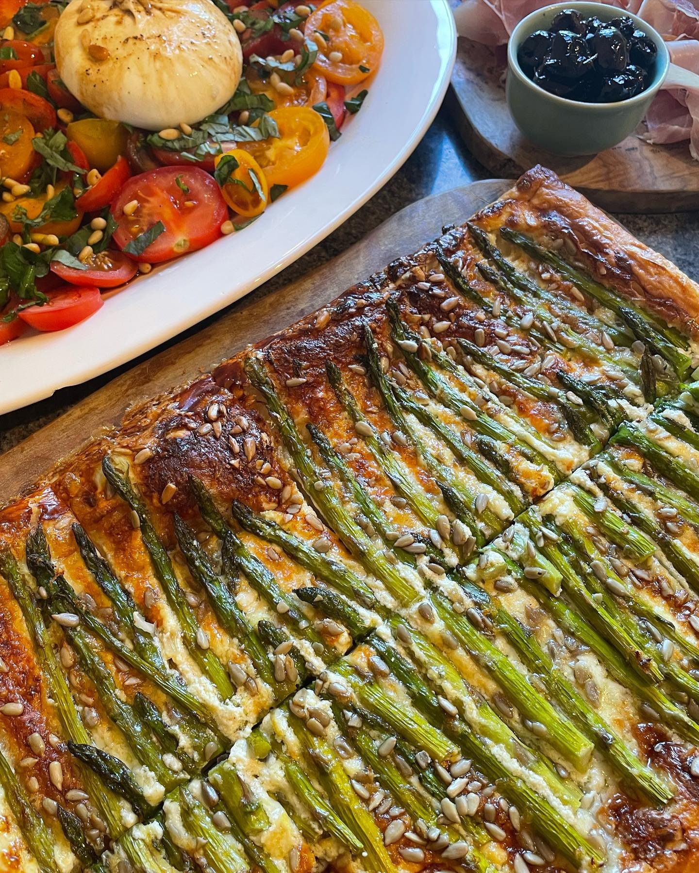 A summer lunch of Gruy&egrave;re, asparagus and pumpkin seed tarts, burrata with cherry tomatoes and basil oil and a lemon vinaigrette quinoa salad 🍋