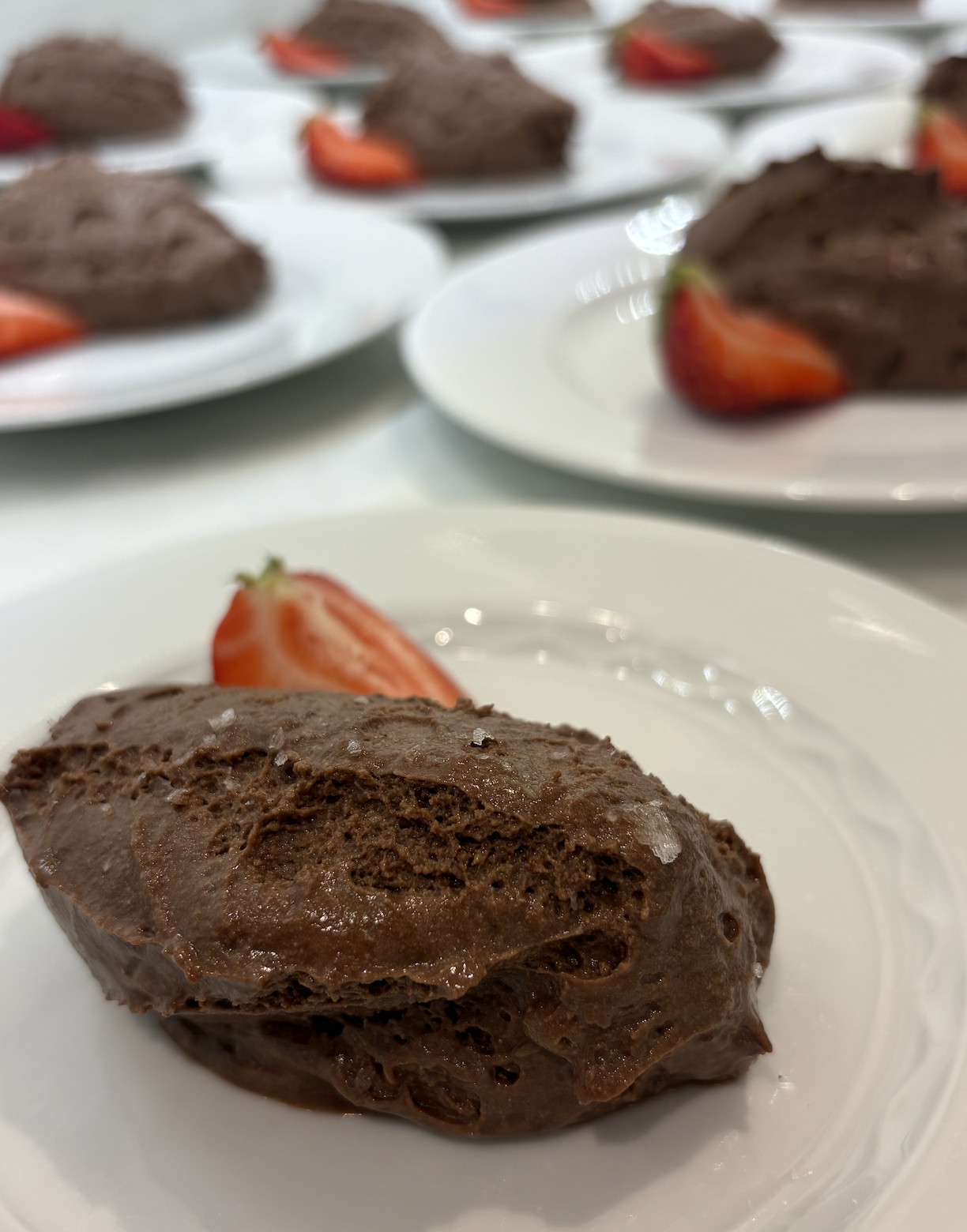 Chocolate dessert with a strawberry slice on a white plate.