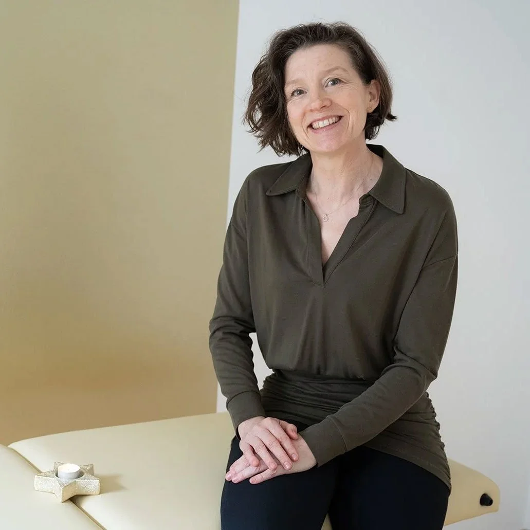 Porträt von Sandra Stark. Sie schaut freundlich, lachend direkt in die Kamera, trägt eine dunkelgrün/ braune Bluse, hat braune, kinnlange Haare.