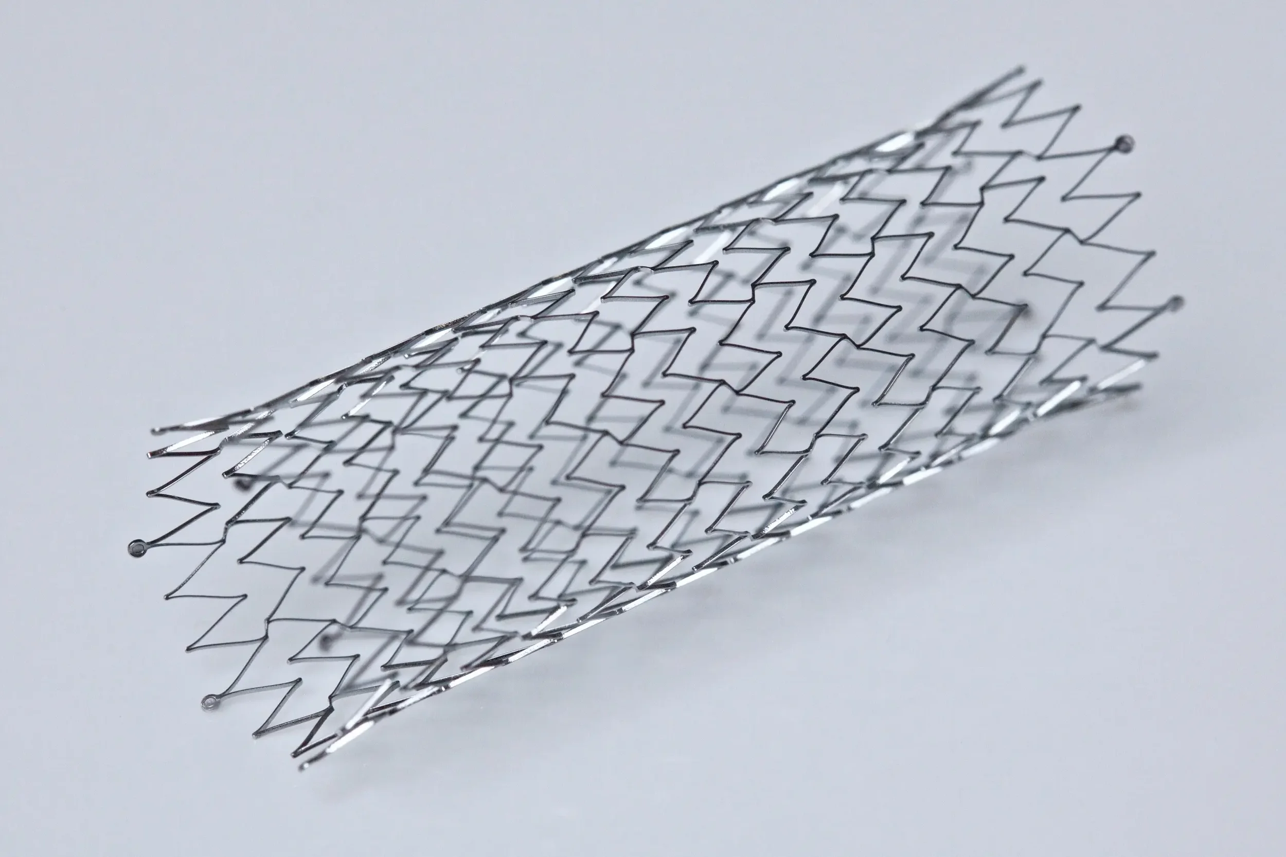 A vascular stent, positioned on a plain white surface.