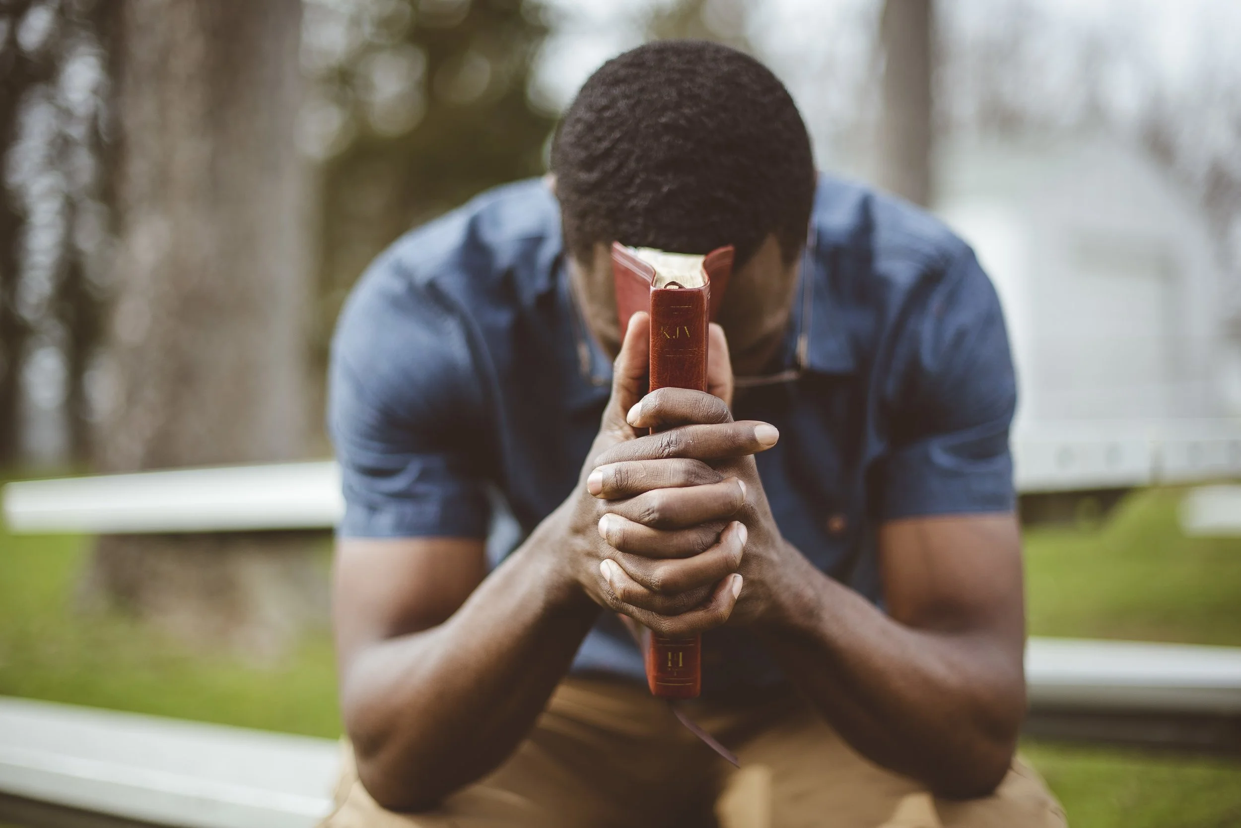 young-african-american-male-sitting-with-closed-eyes-with-bible-his-hands.jpg
