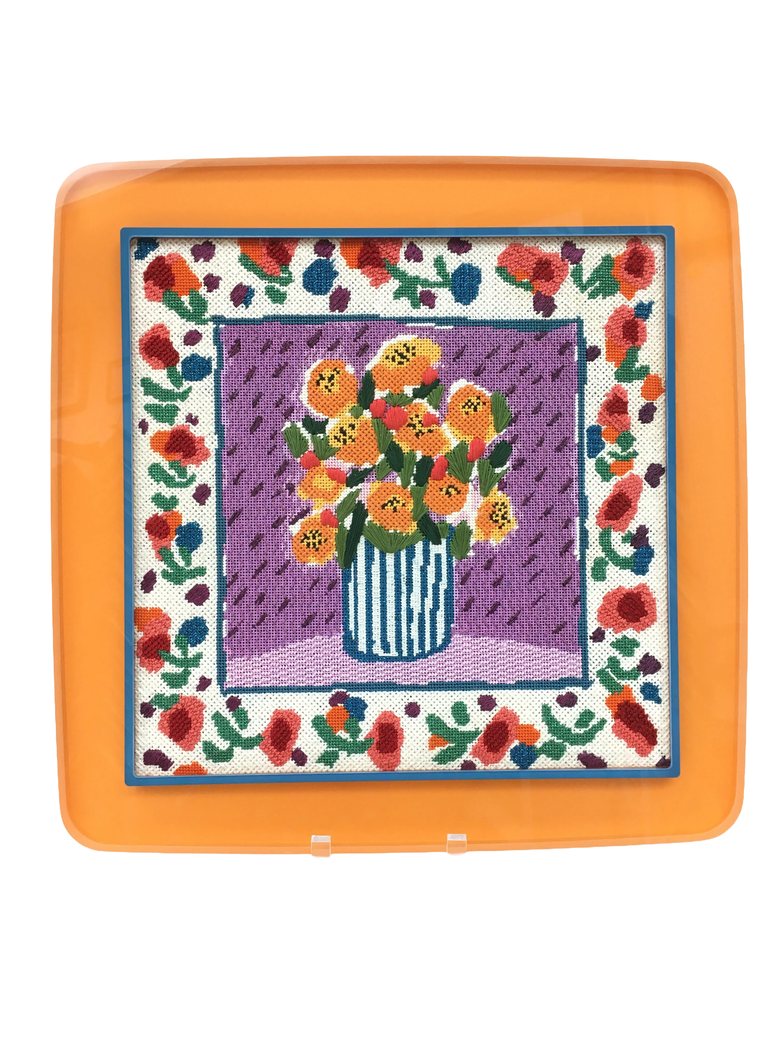 Photo of boldly colored floral stitchery in an orange and blue acrylic frame