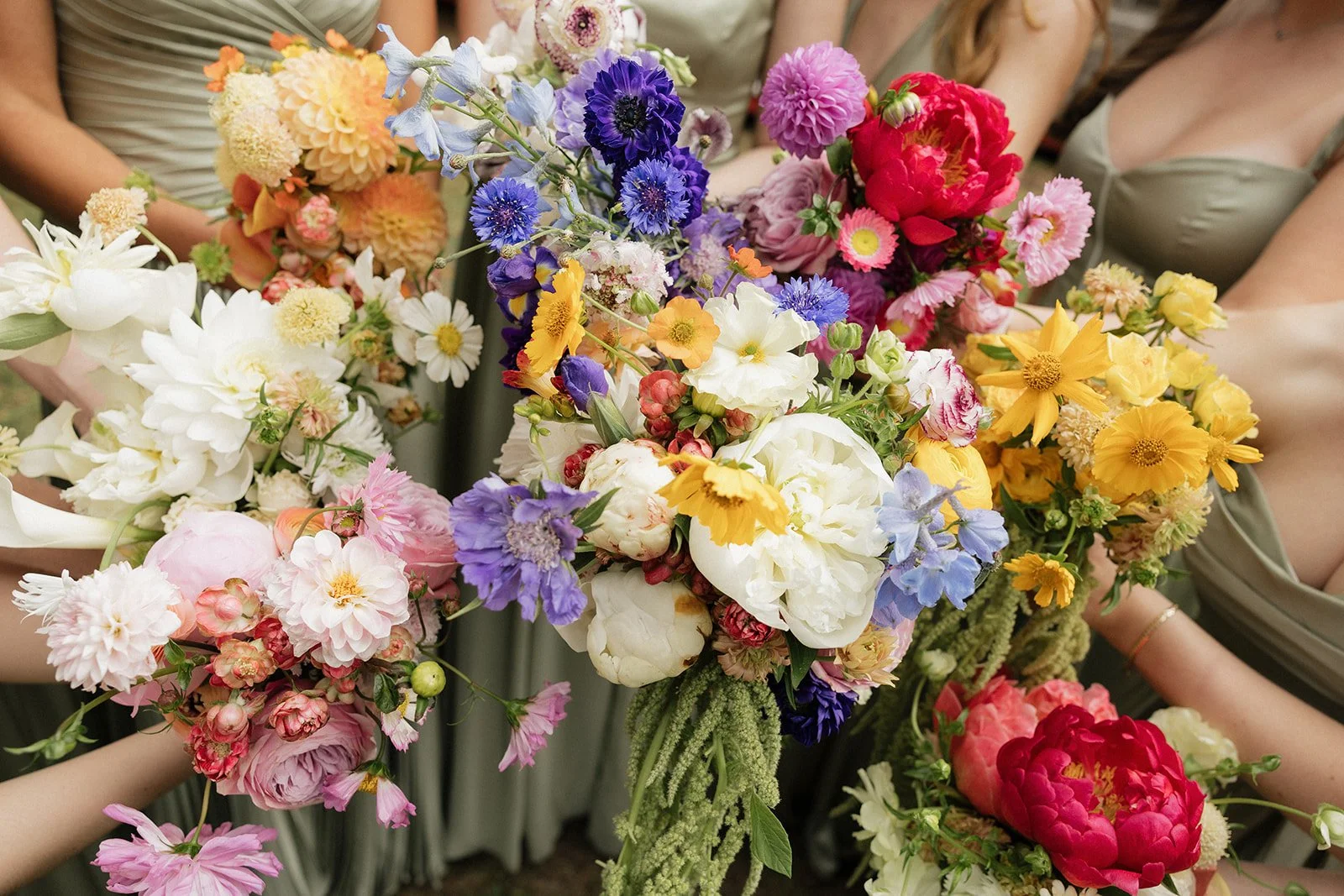 Multiple colorful bouquets of various flowers being held by women, with some women wearing elegant dresses.