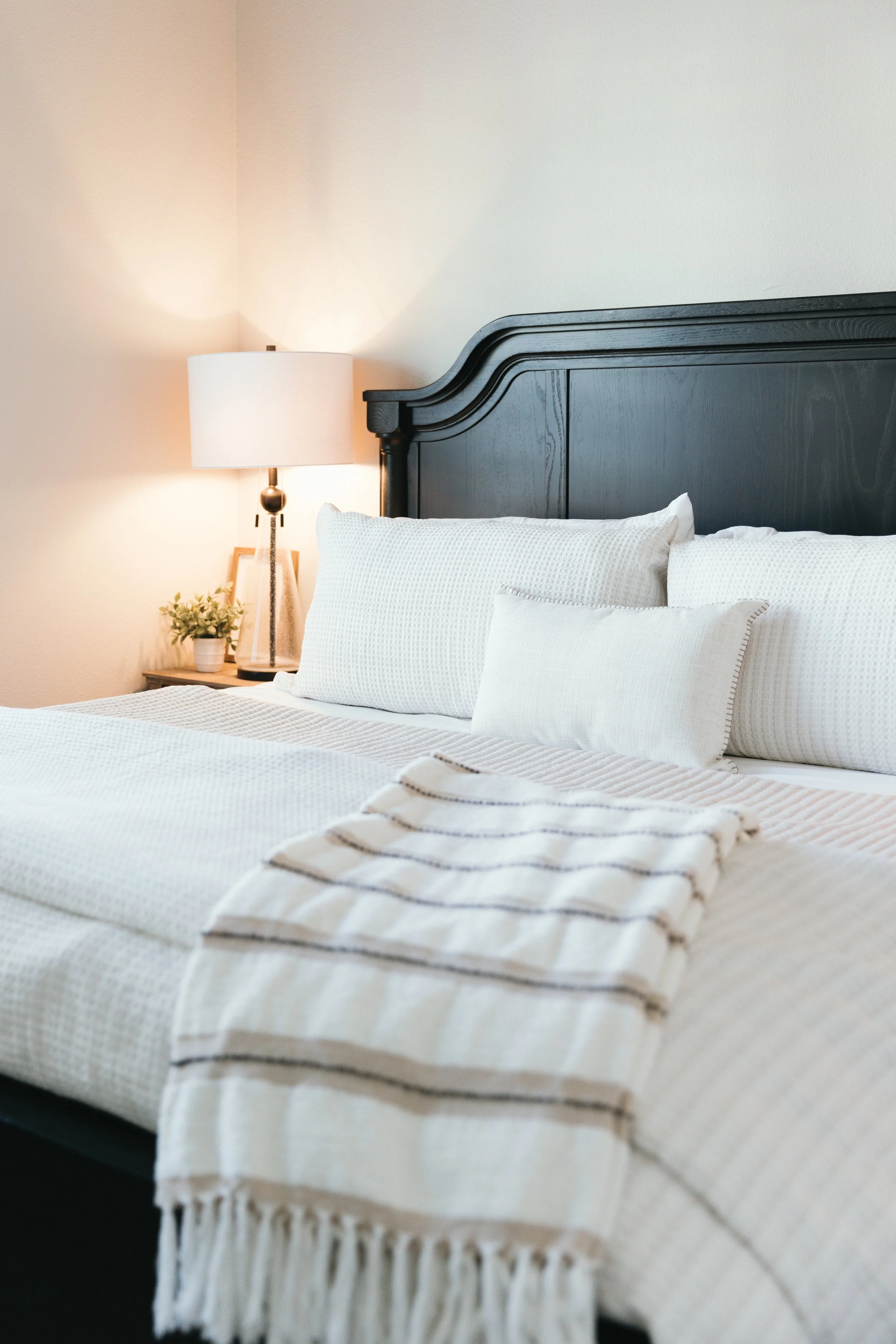 Serene guest bedroom with layered neutral linens and accent pillows-staged by Merriment by Design Dallas