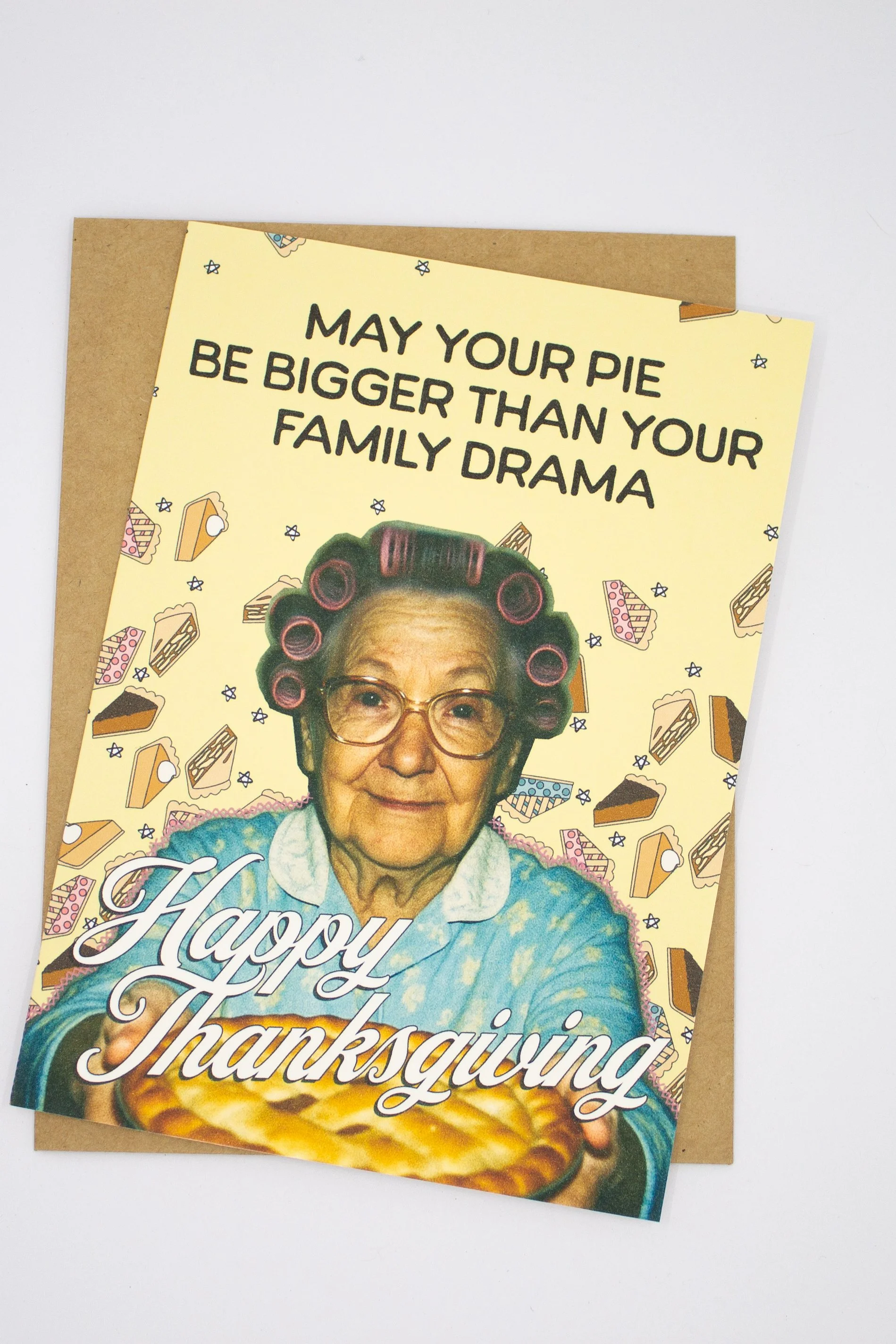 This funny Thanksgiving greeting card features a sweet vintage grandma proudly presenting a homemade pie with the delightfully optimistic wish: "May your pie be bigger than your family drama."
