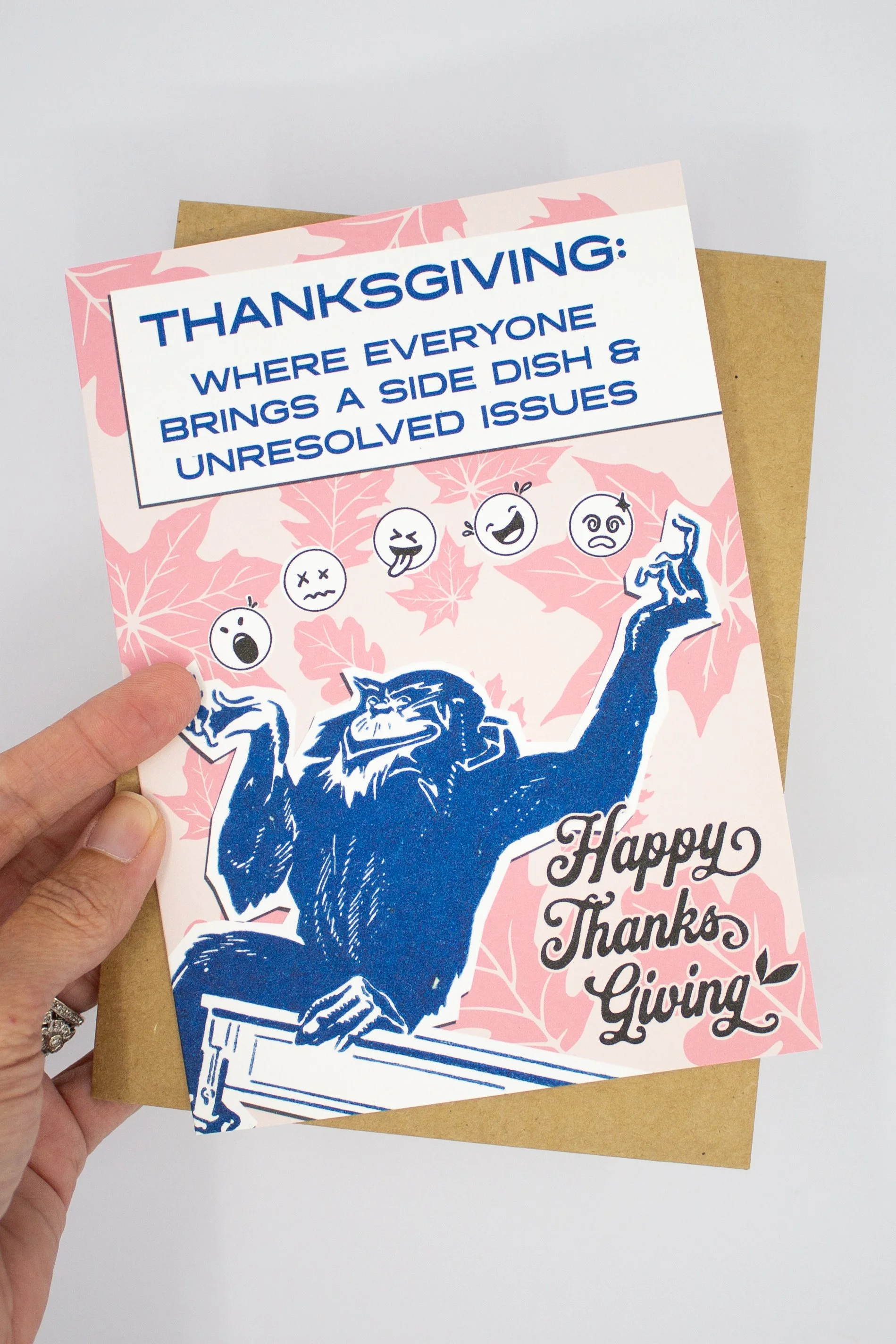 This funny Thanksgiving greeting card features a colorful monkey juggling a collection of emoji faces, capturing the emotional balancing act that is Thanksgiving dinner.