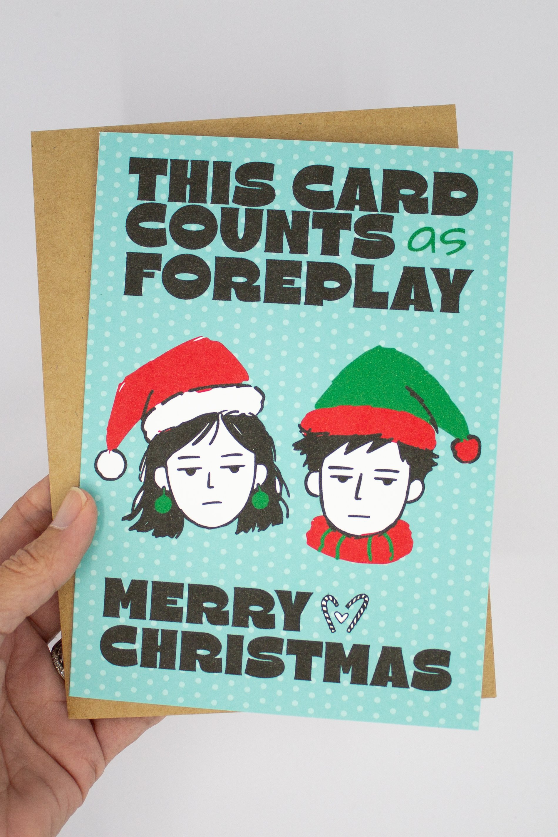 Funny Christmas greeting card featuring illustrated man and woman wearing Santa hats with the saying "This card counts as foreplay."