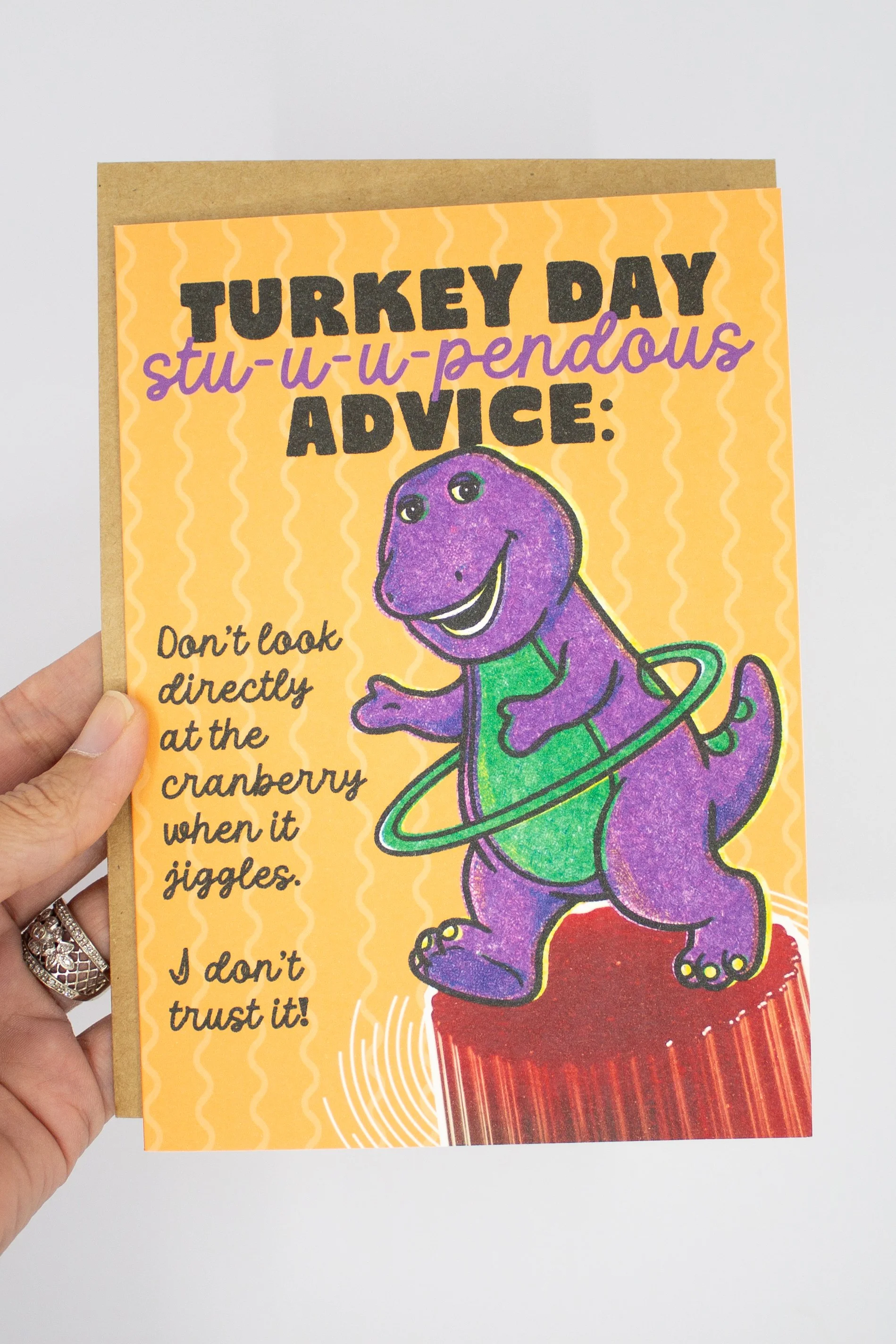 This Thanksgiving card for friends, siblings, coworkers, or fellow 90s survivors, features features Barney the purple dinosaur hula-hooping on top of canned cranberry jelly