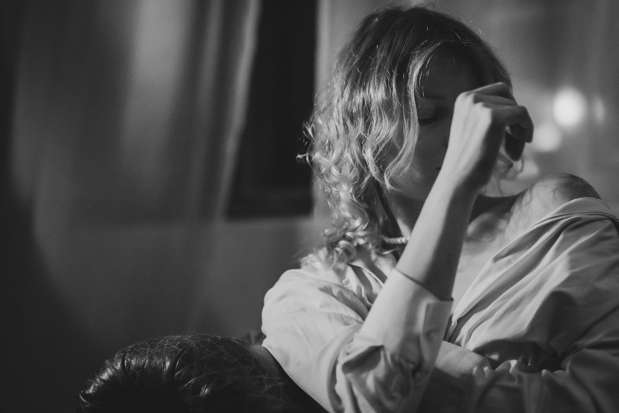 Black and white photo of a person with curly hair, resting with a hand on their face.