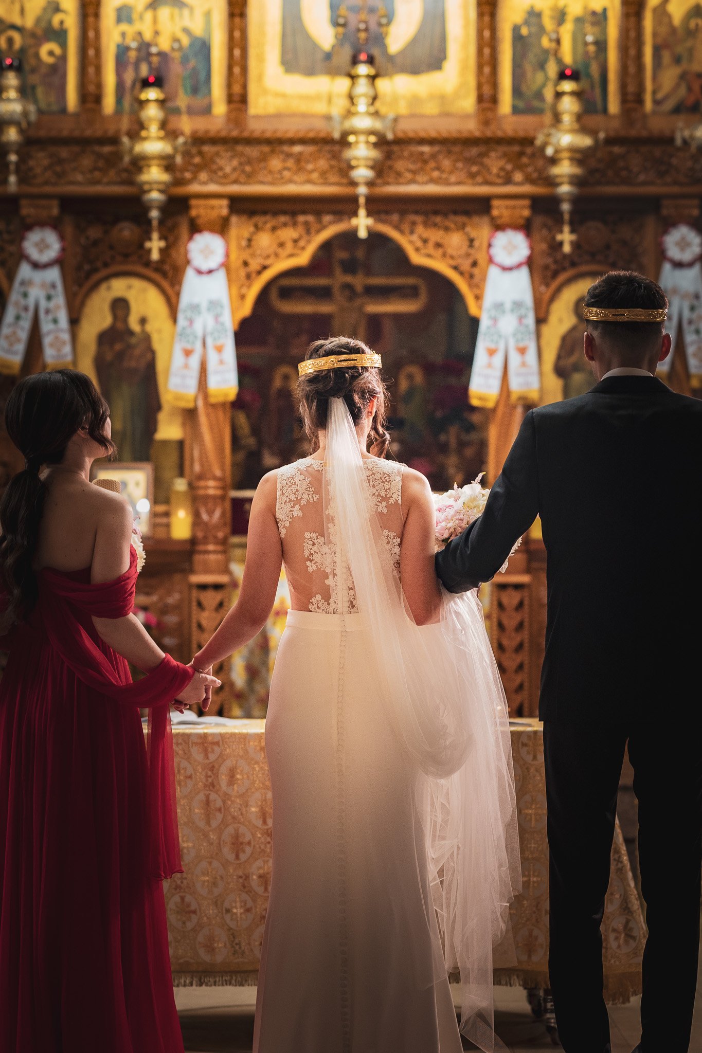 Orthodox wedding ceremony, bride in white gown and veil, groom in black suit with crown, ornate church interior, religious icons.