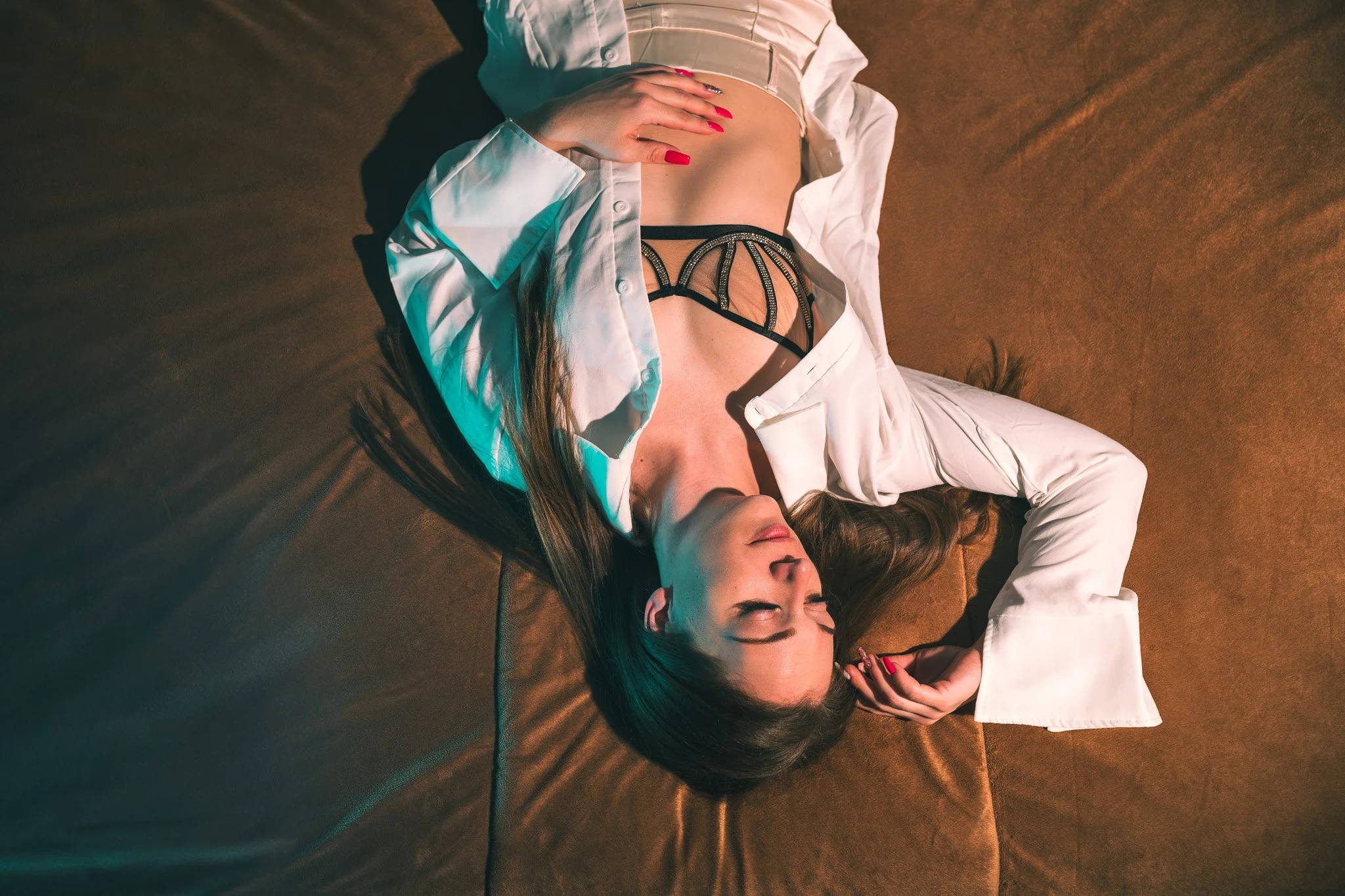 A woman lying on a brown surface with her eyes closed.
