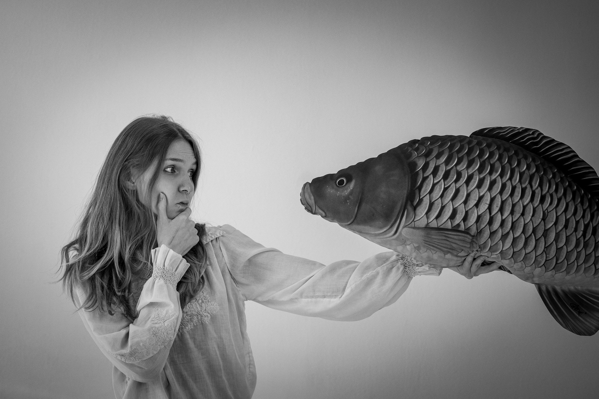 Woman holding and looking at a large fish in black and white photo
