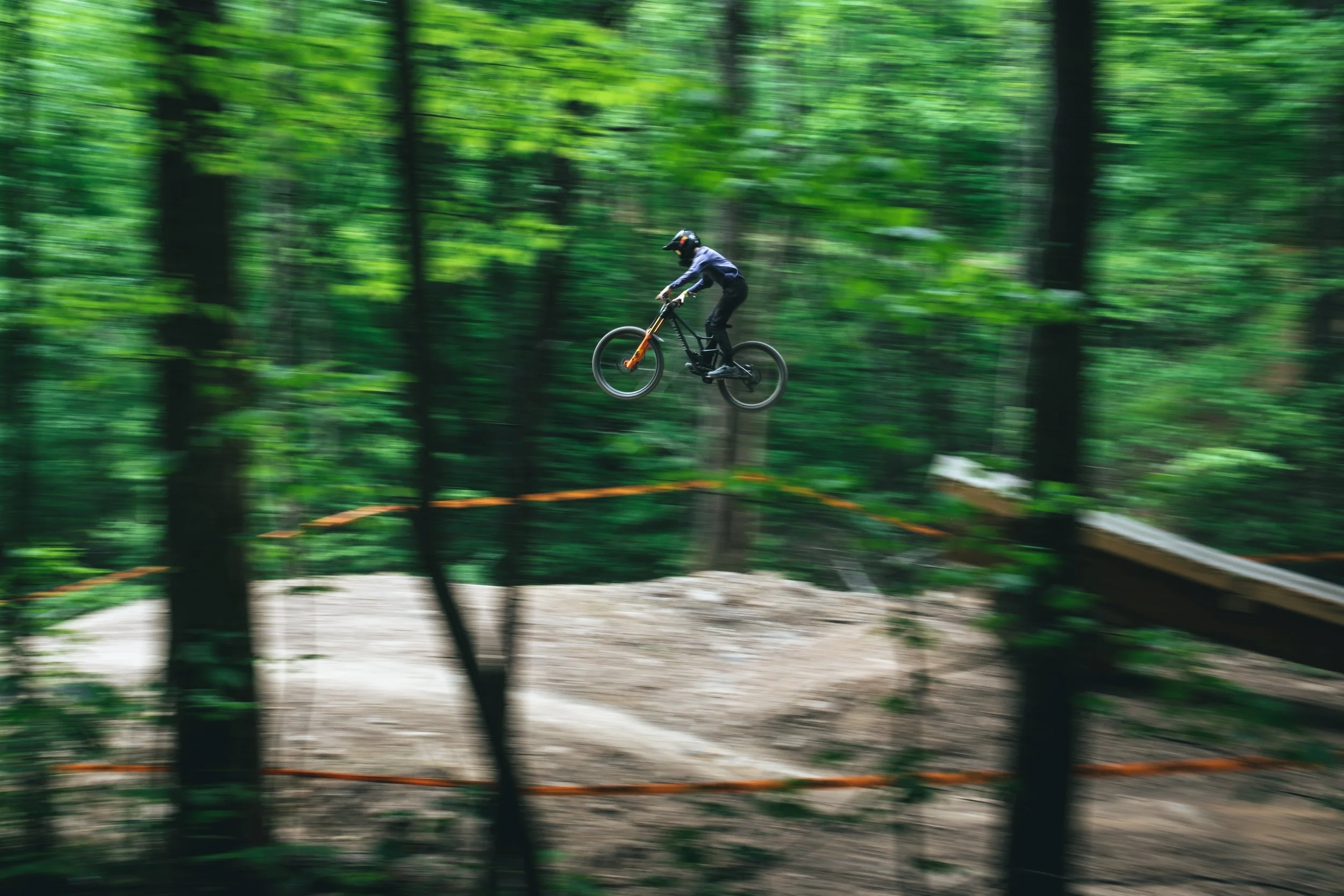 Person riding a mountain bike on a trail through a lush green forest.