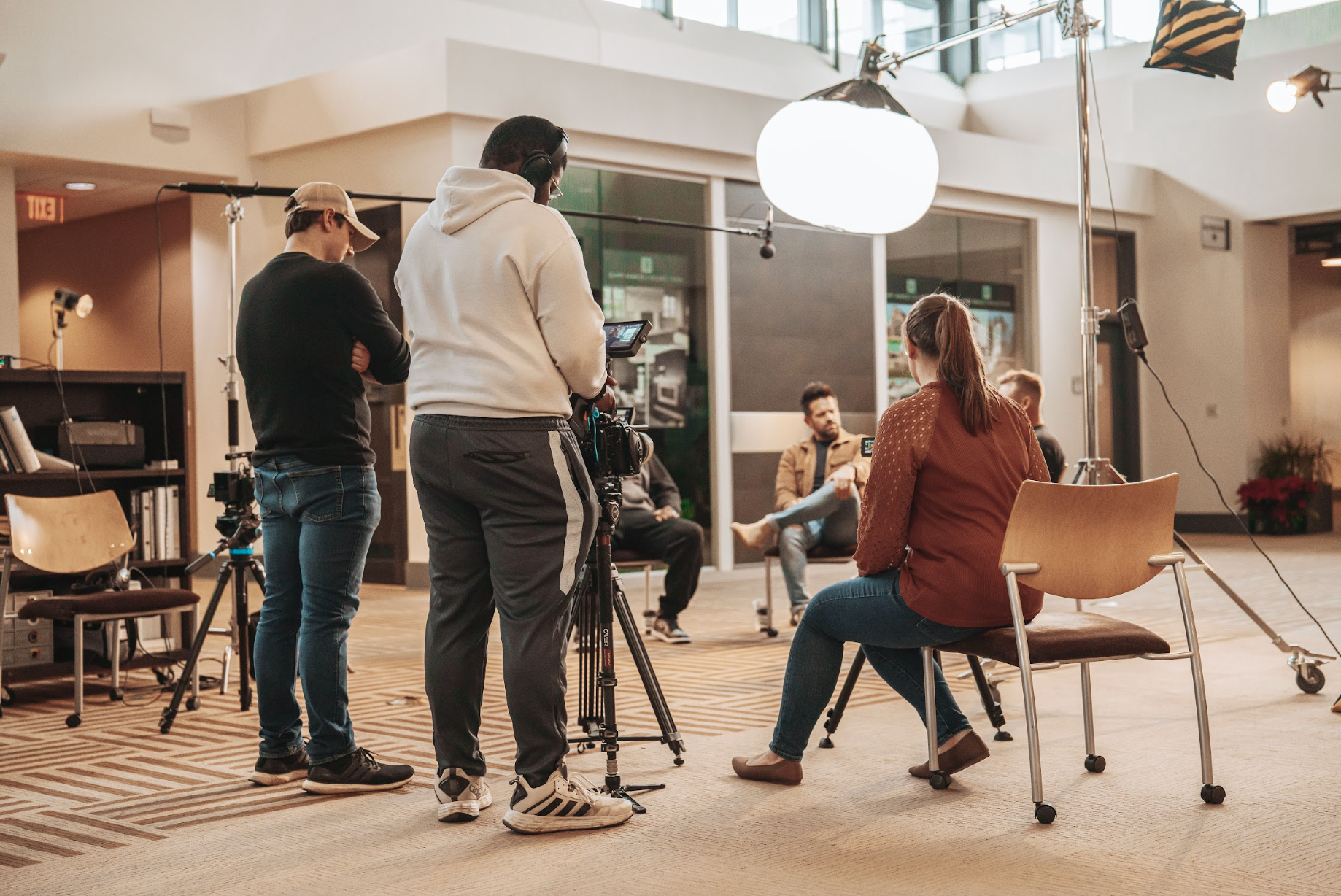 Film crew and interview setup with cameras and lighting equipment.