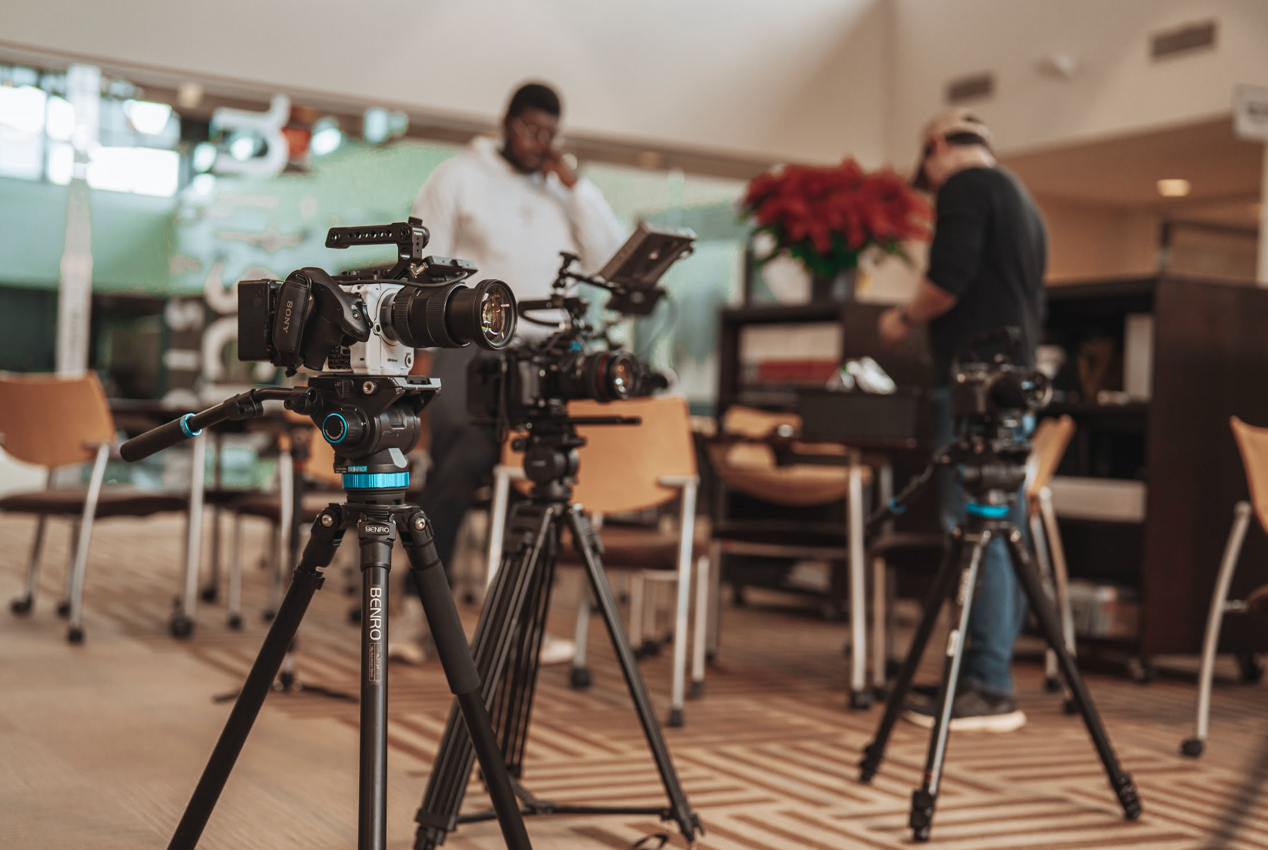Professional cameras on tripods in a studio with people in the background.