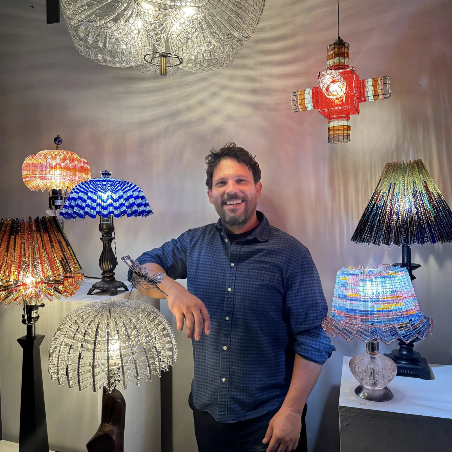 Cory Clinton standing with his creations unique lighting fixtures
