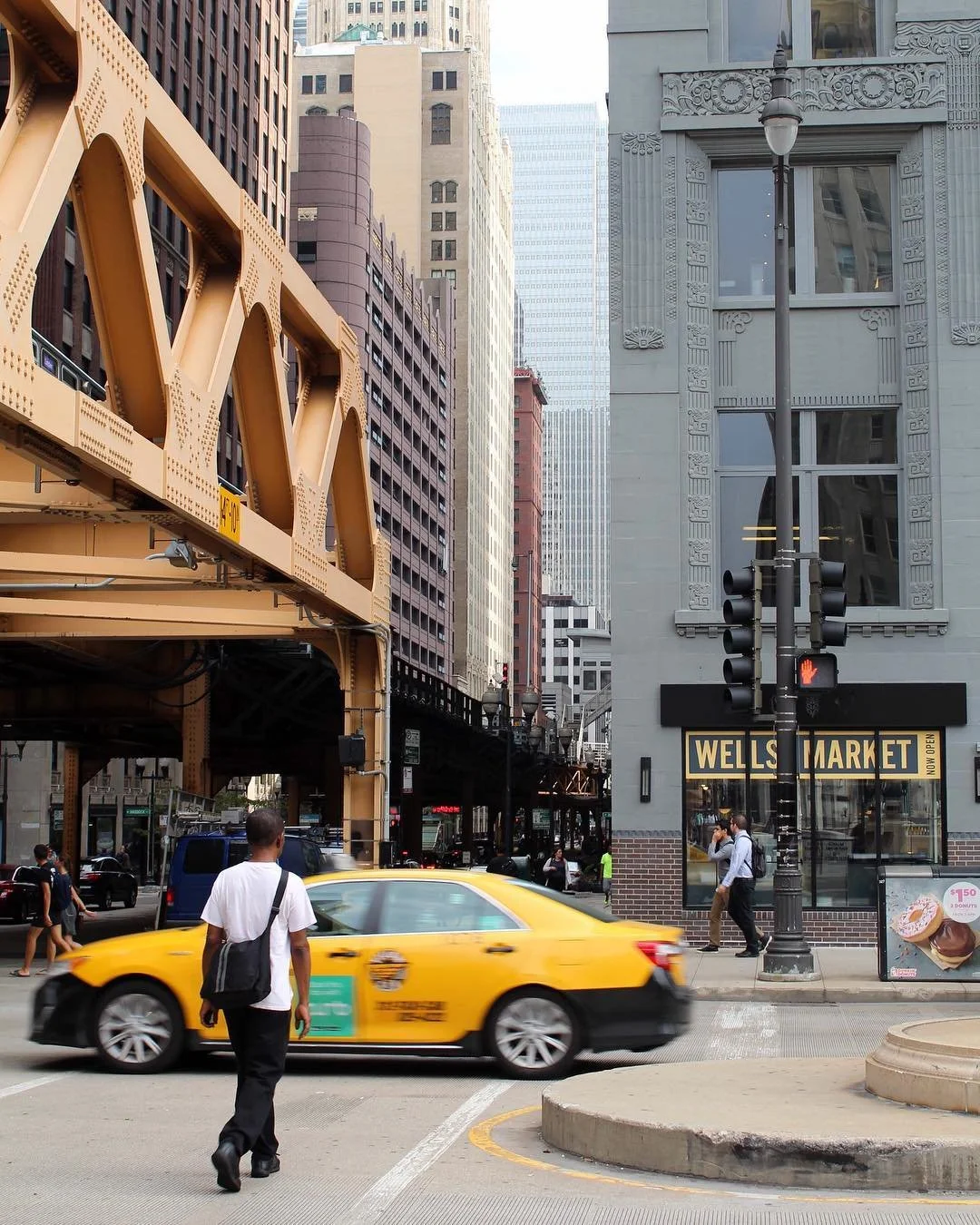 City street outside a restaurant with a yellow taxi passing by.