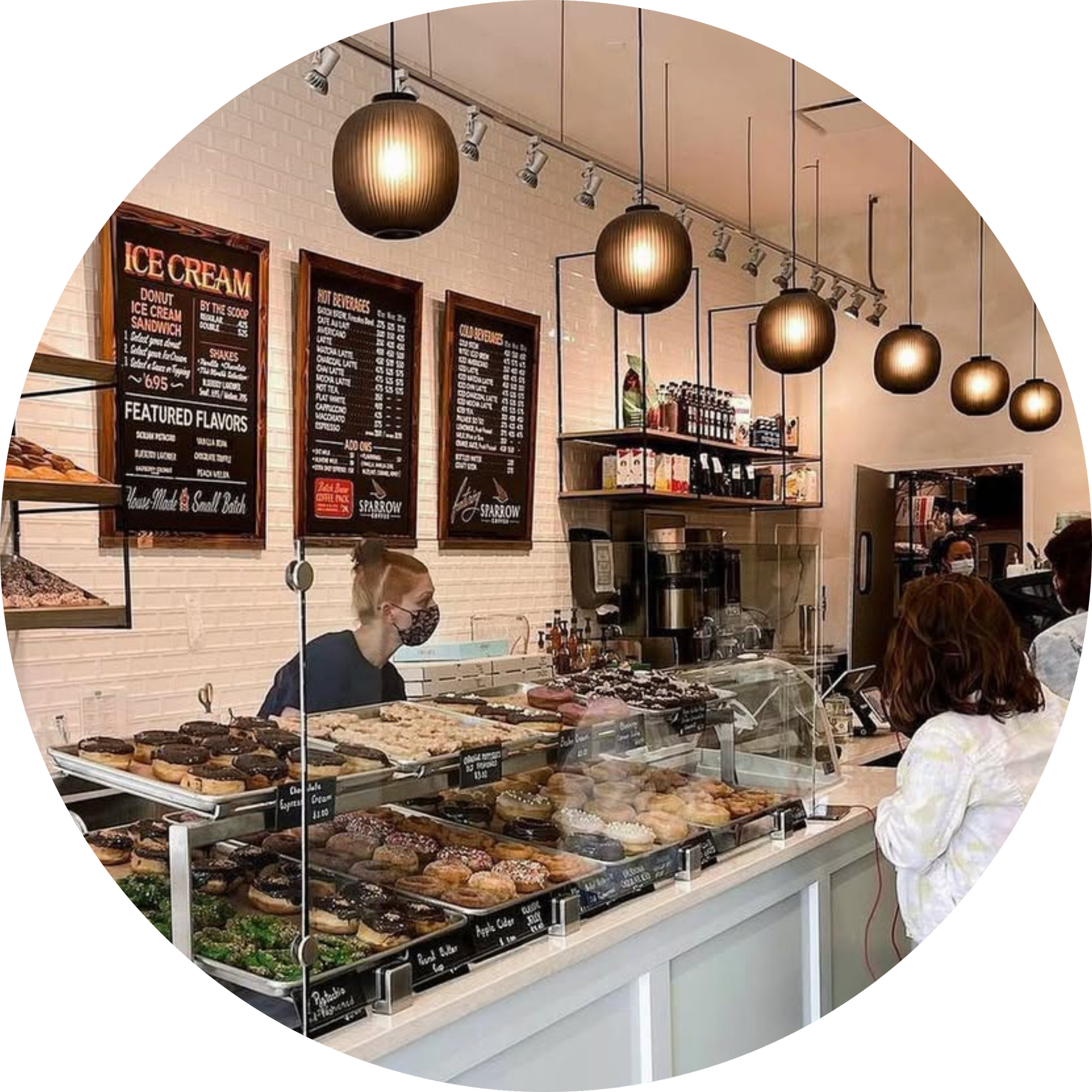 Bakery display counter filled with pastries beneath hanging menu boards.