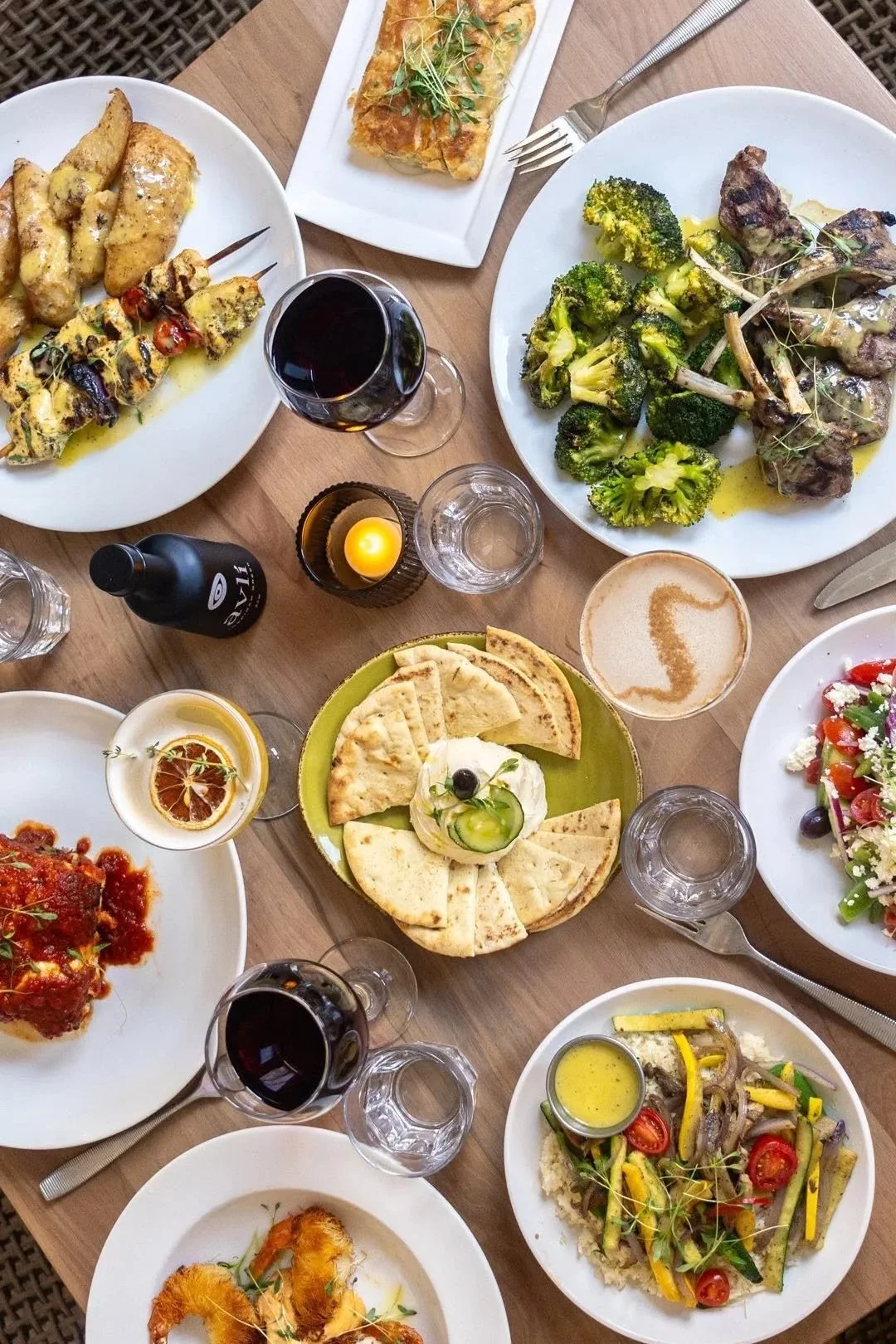 Overhead view of a shared meal with dips, salads, bread, and small plates.
