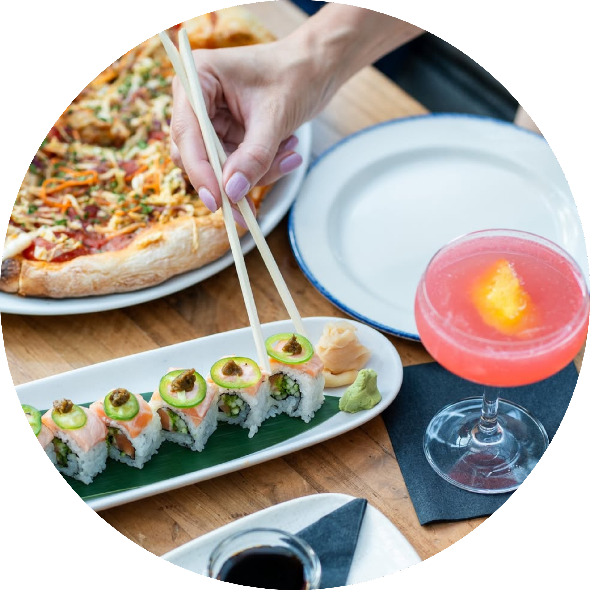 Pizza, appetizers, and a cocktail arranged on a table.