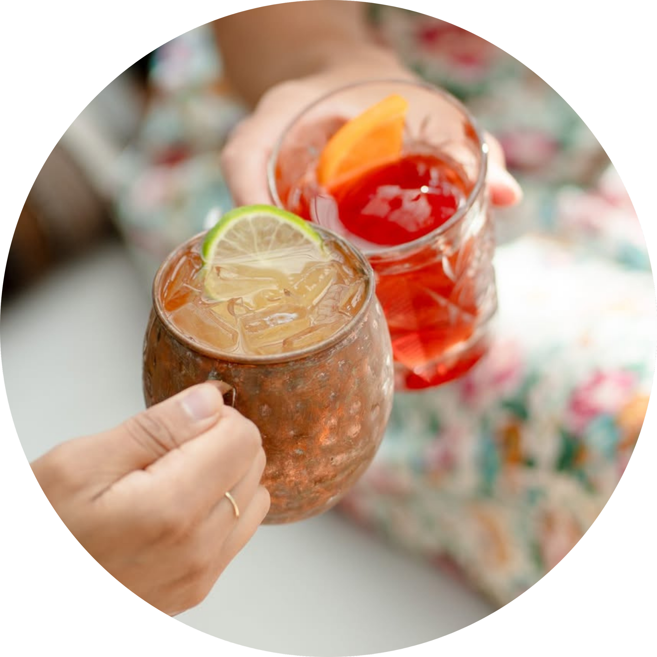 Two guests holding colorful cocktails garnished with citrus.