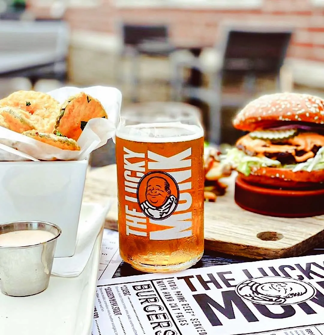 Burgers, fries, and a glass of beer served on a restaurant table.