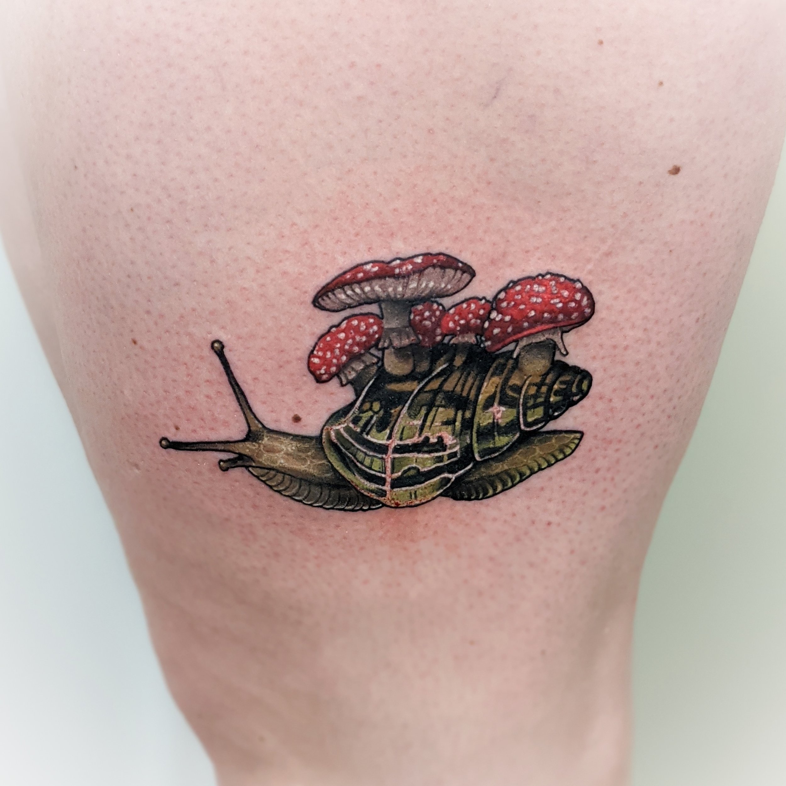 Tattoo of a snail with mushrooms on its shell