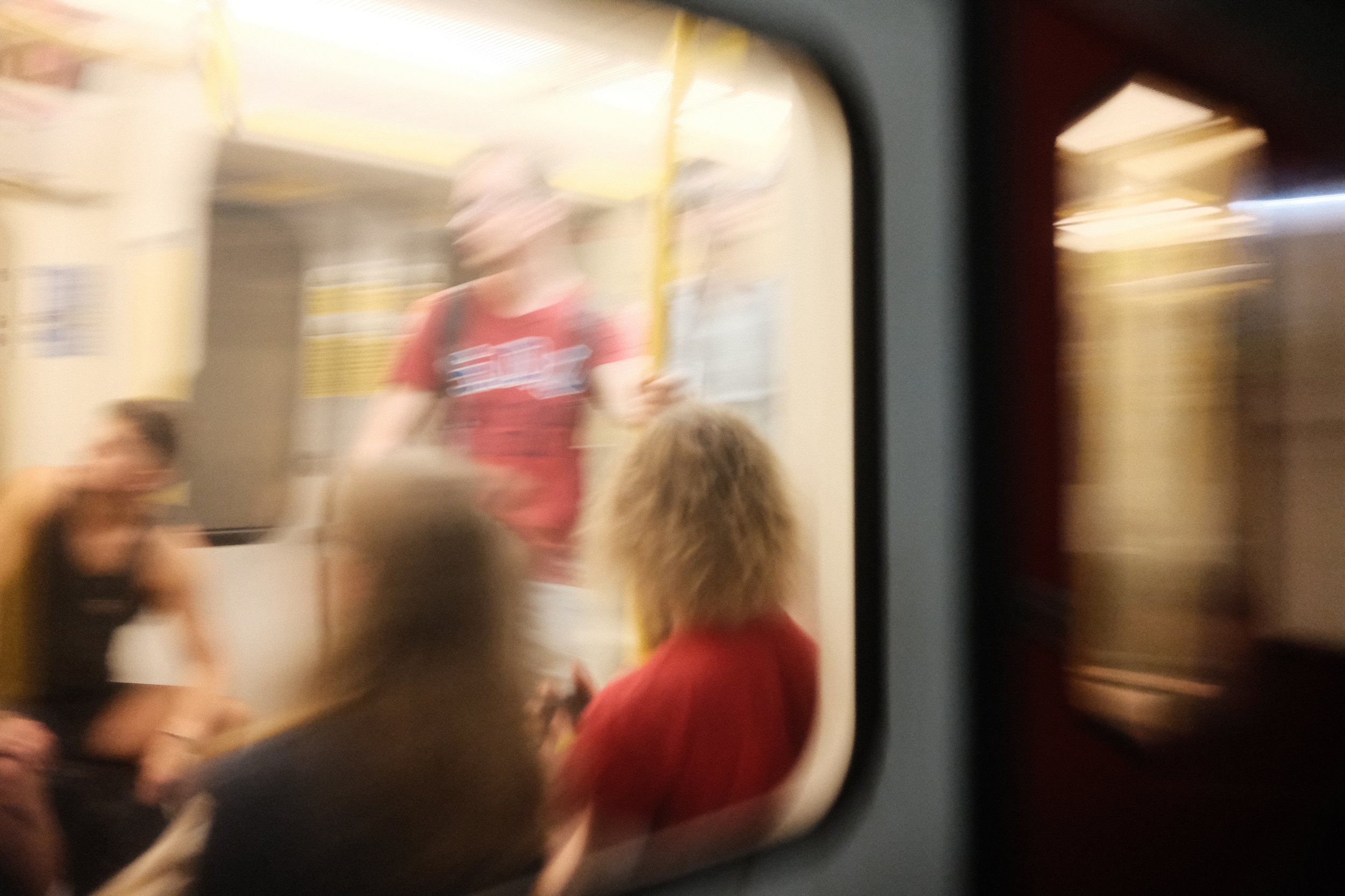 Blurred reflection of people in a mirror with yellow poles and indoor lighting.