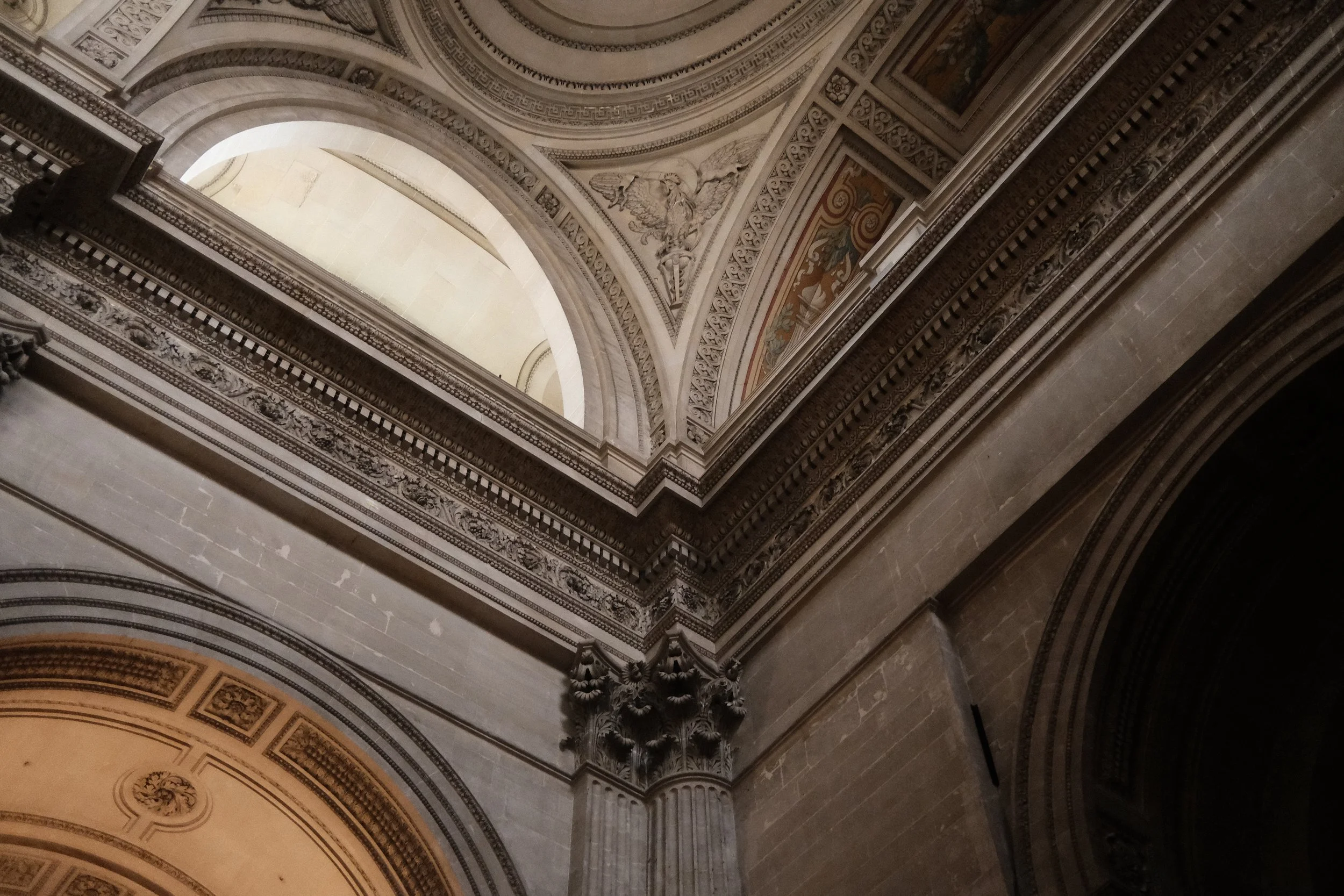 The ornate ceiling and archways of a historic building, decorated with intricate carvings and artwork.