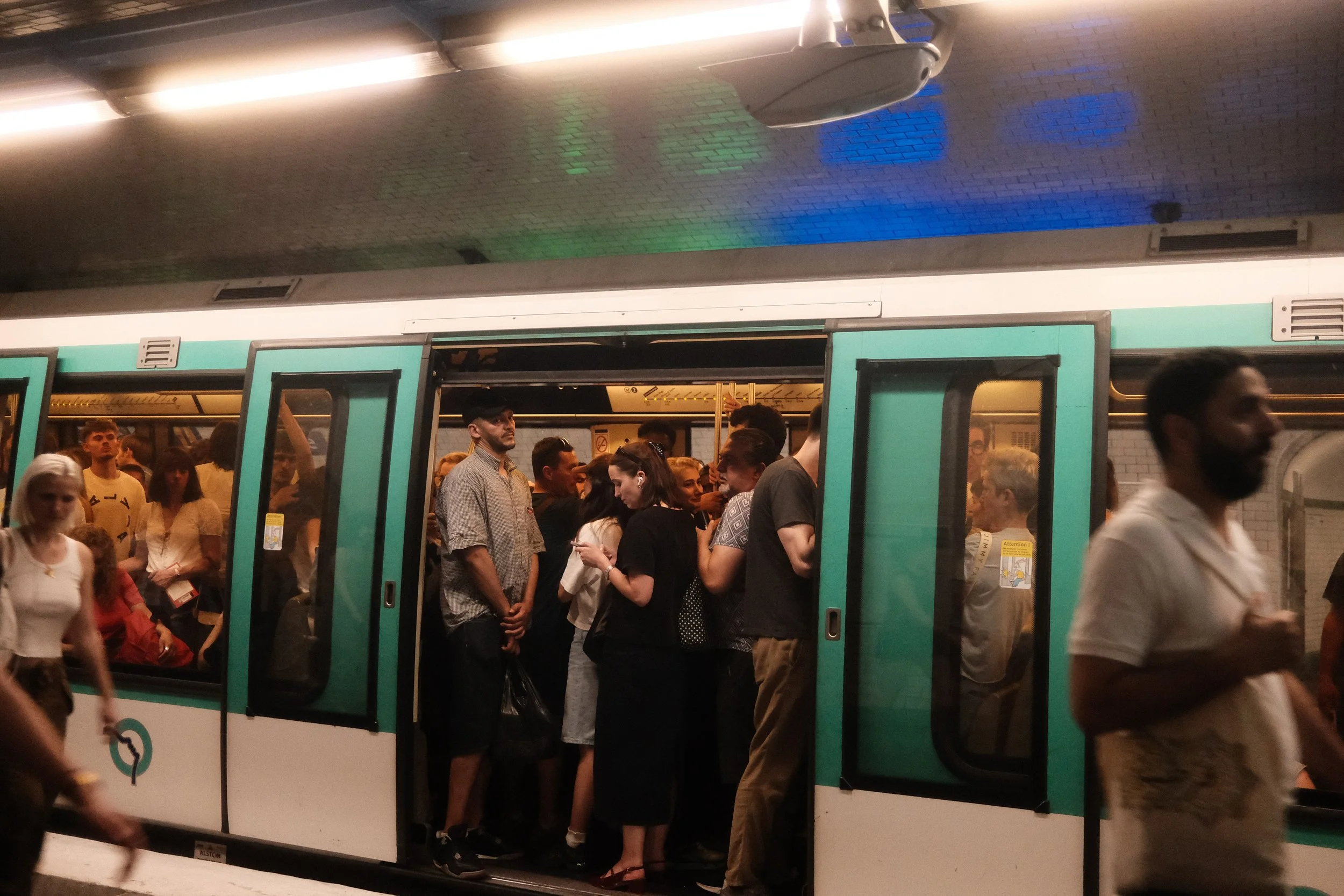 People crowded inside and around a subway train at a station, some waiting to board while others are exiting.