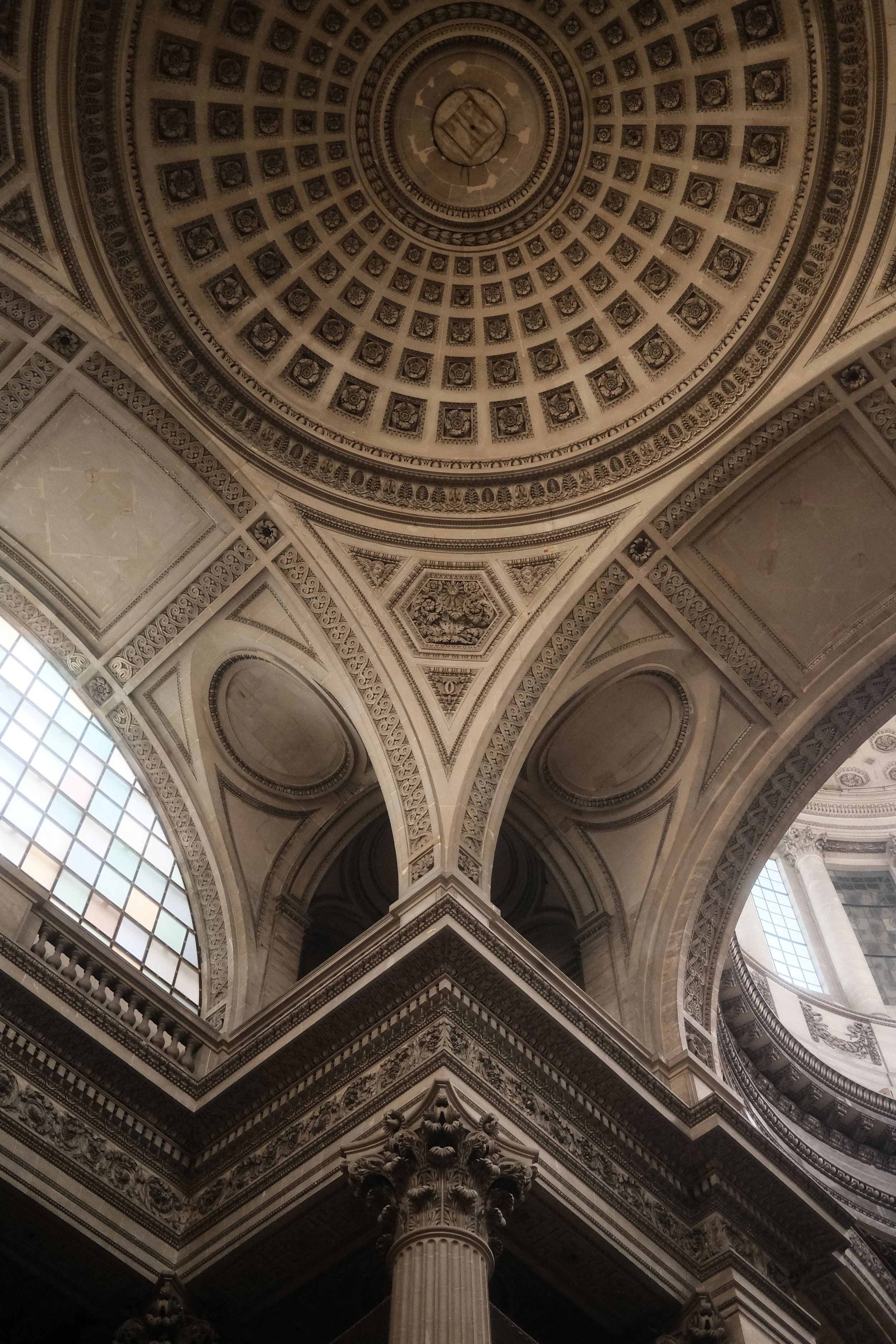 Interior view of a grand, ornate dome ceiling with detailed architectural patterns and a central decorative element, supported by a classical column.