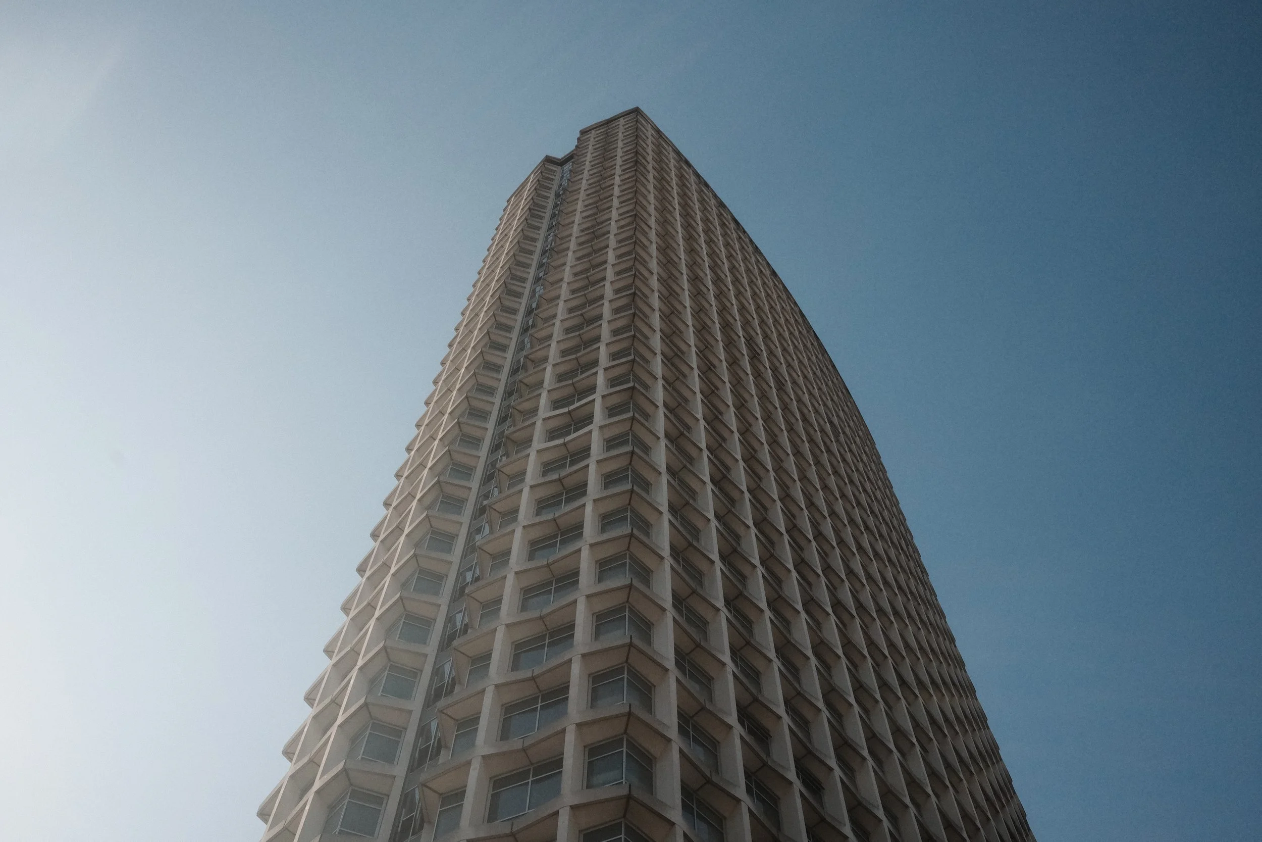 A tall residential building viewed from the ground with a clear sky background.