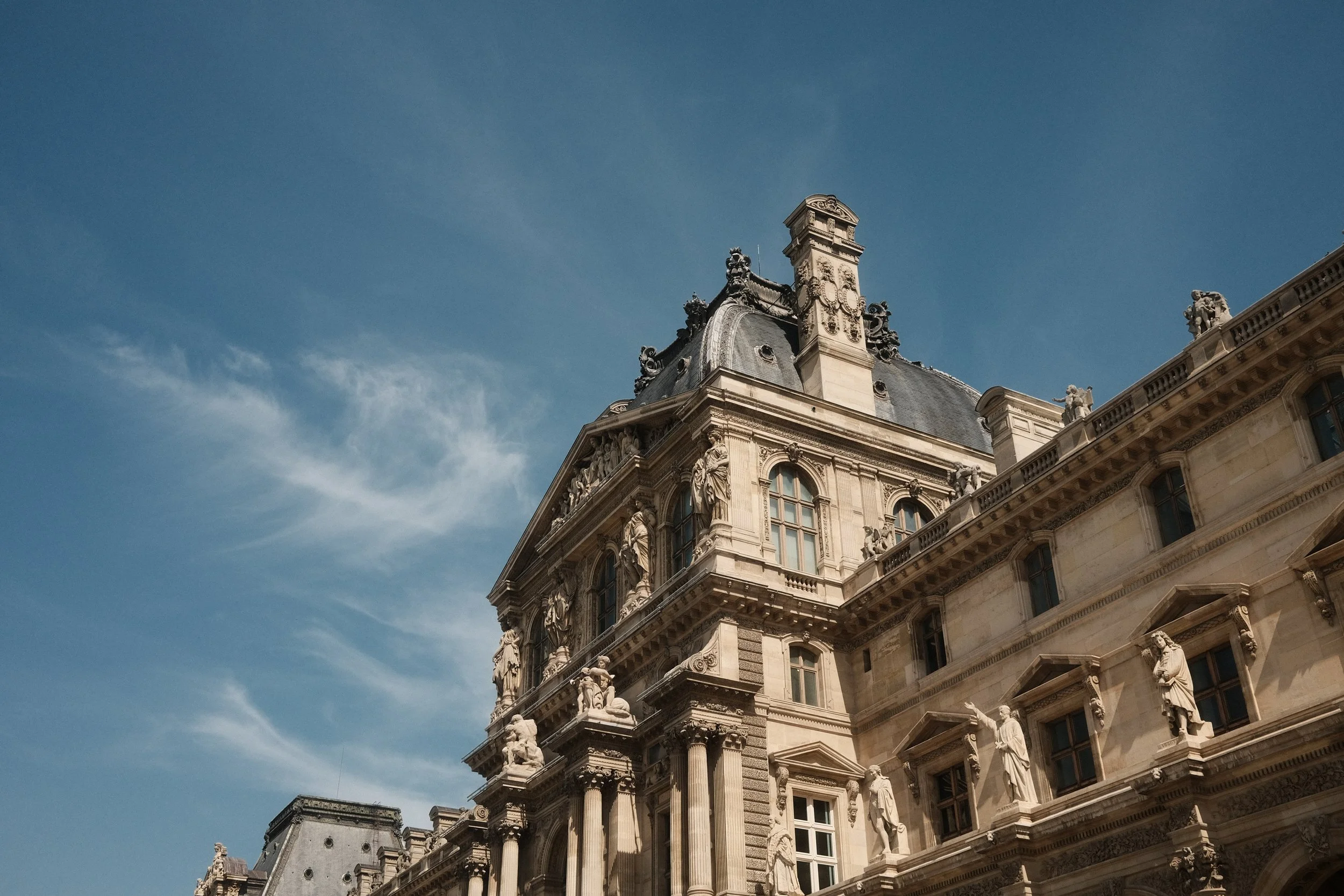 A historic ornate building with sculptures and detailed architectural elements under a blue sky.