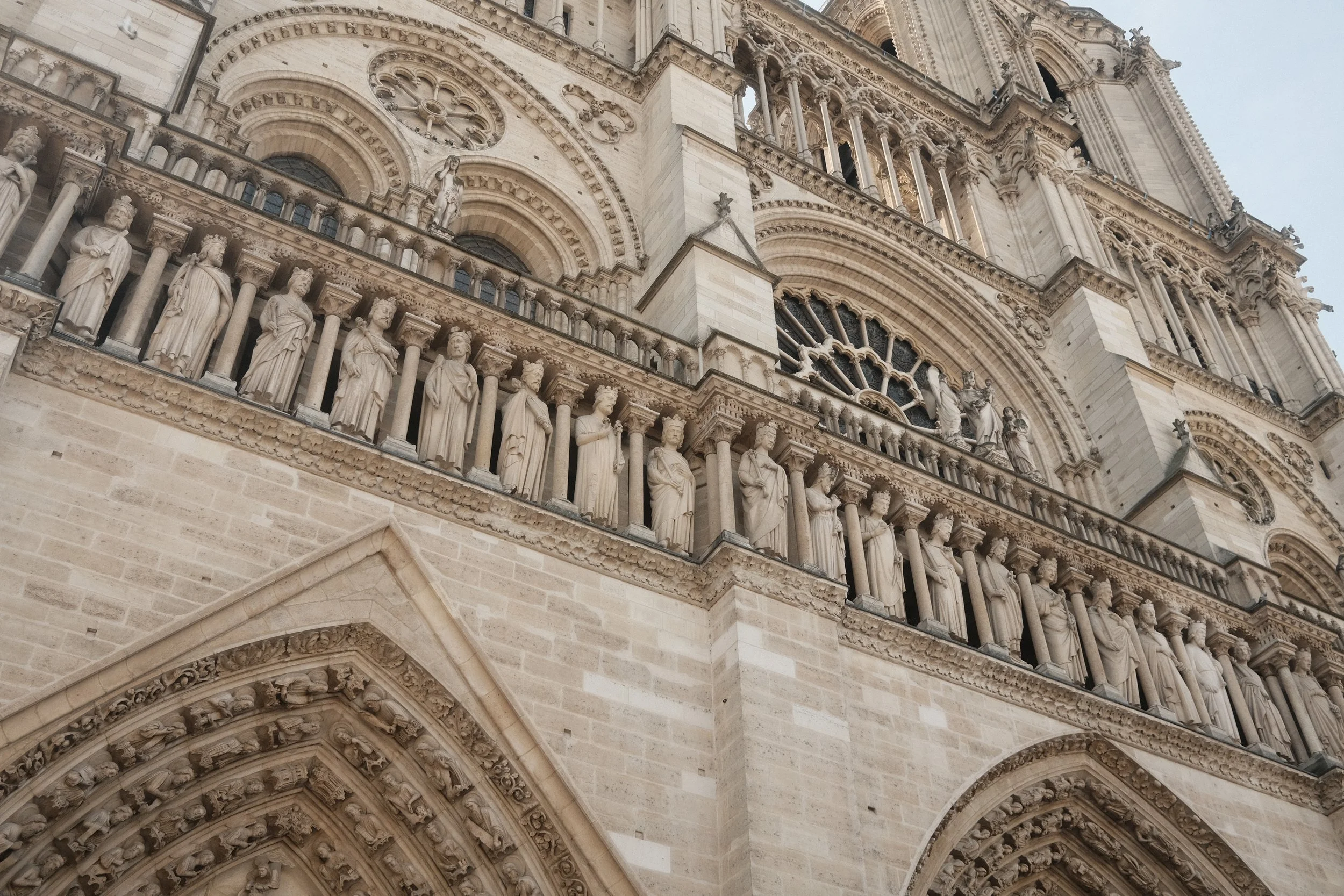 Close-up of an ornate Gothic cathedral facade with numerous carved statues and sculptures on multiple levels above an arched entryway.