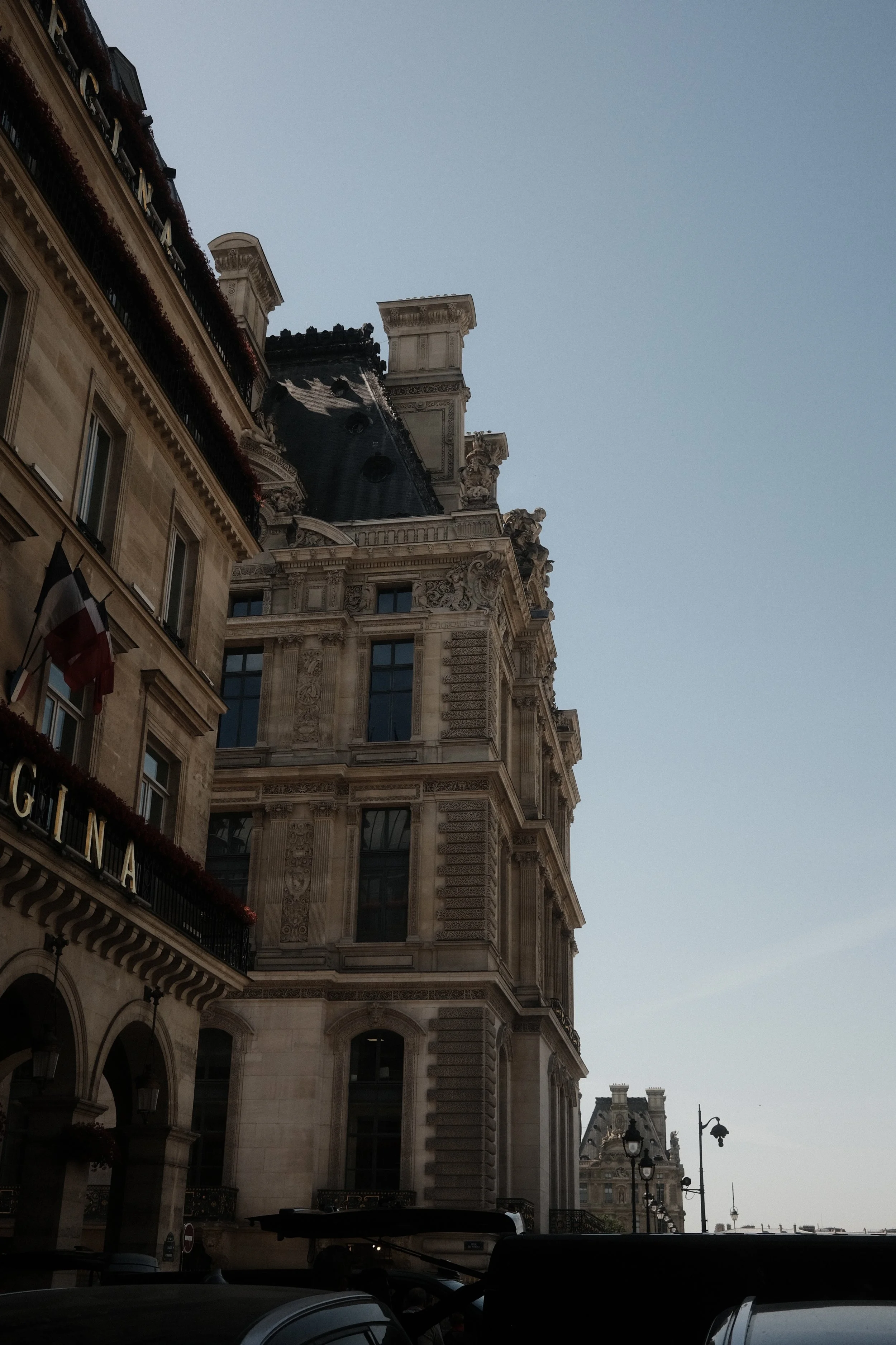 A view of ornate, classic Parisian architecture with detailed stone facades, balconies, and chimneys, taken during the day with a clear sky.