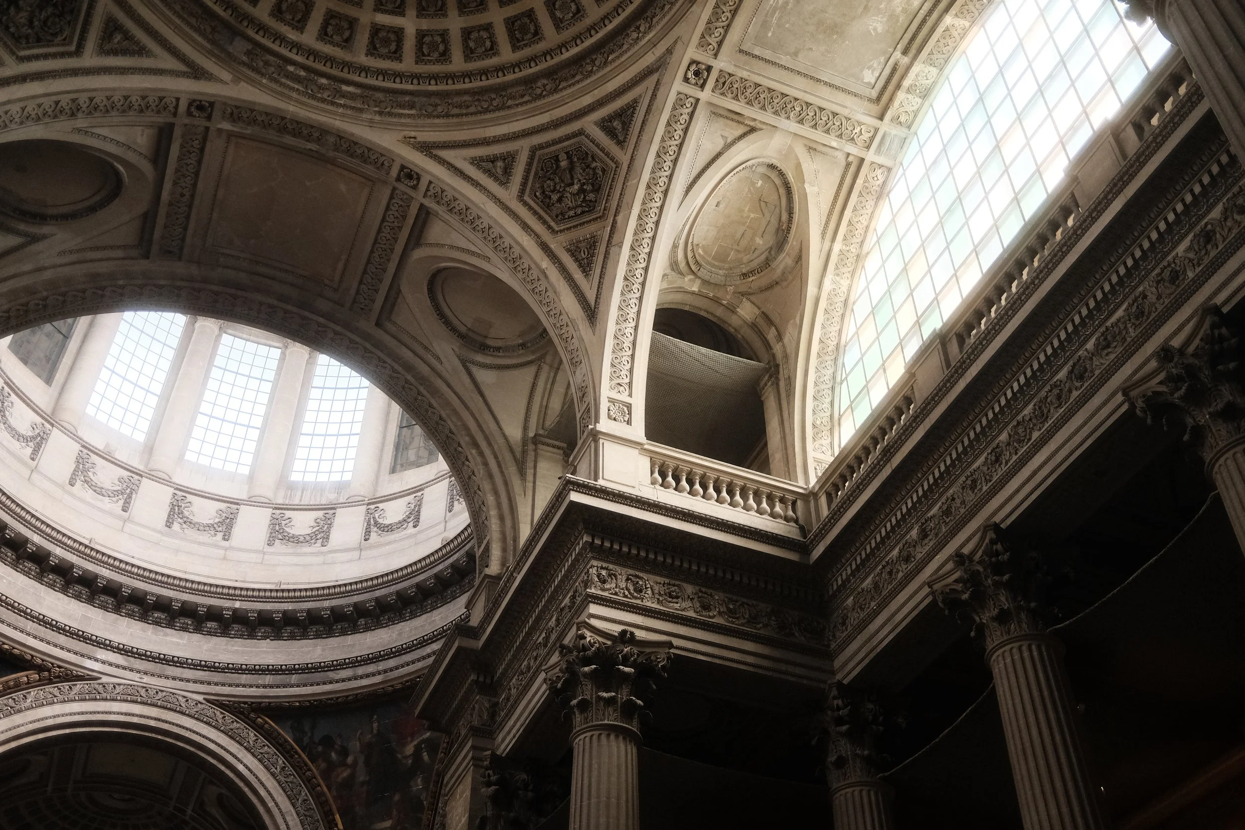Interior view of a grand historic building with ornate architectural details, large arched windows, columns, and intricate ceiling decorations.