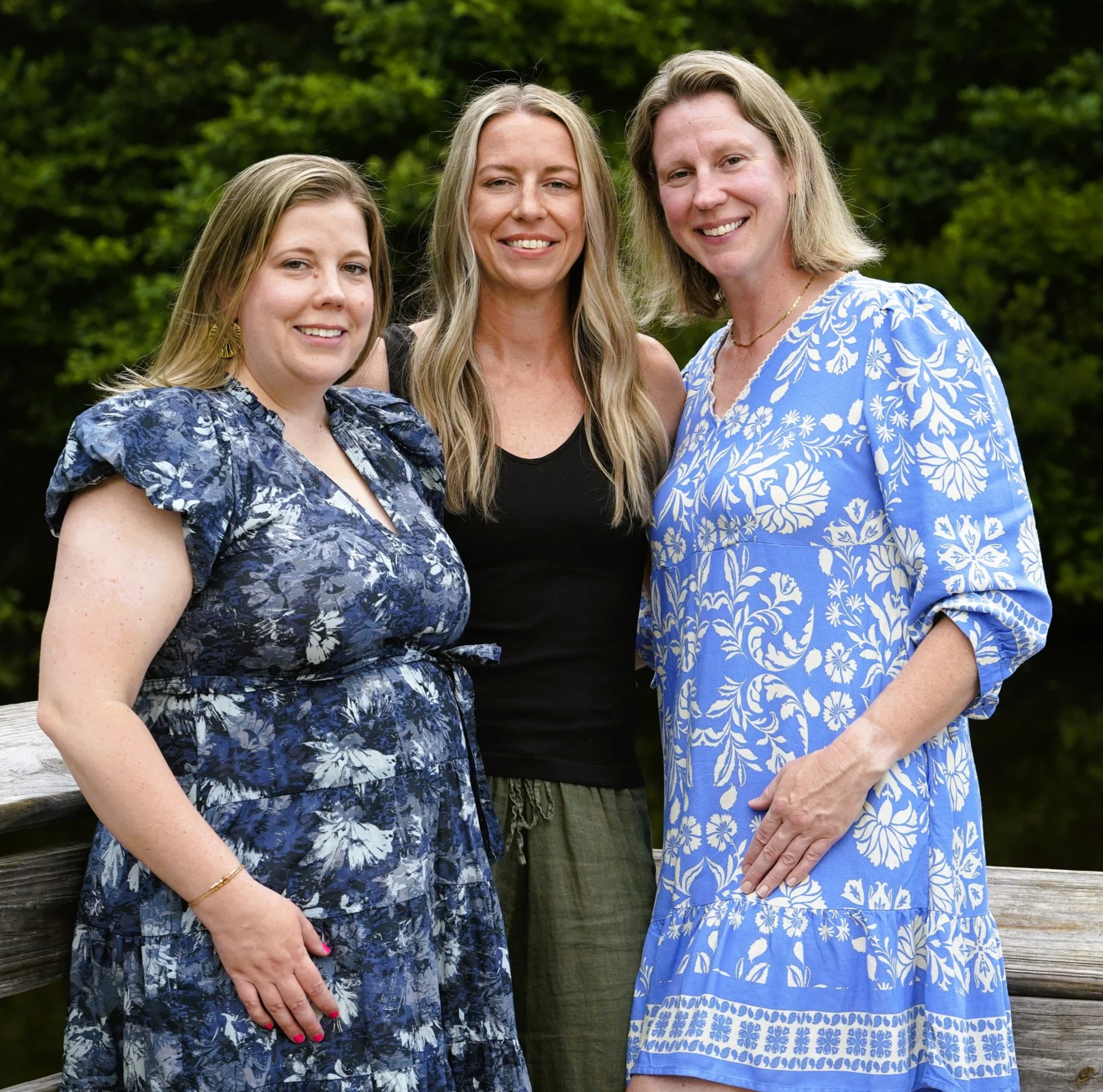 A Raleigh photographer's photo of three sisters for family photos against a background of trees on a wooden dock at Seagroves Park, Apex, North Carolina