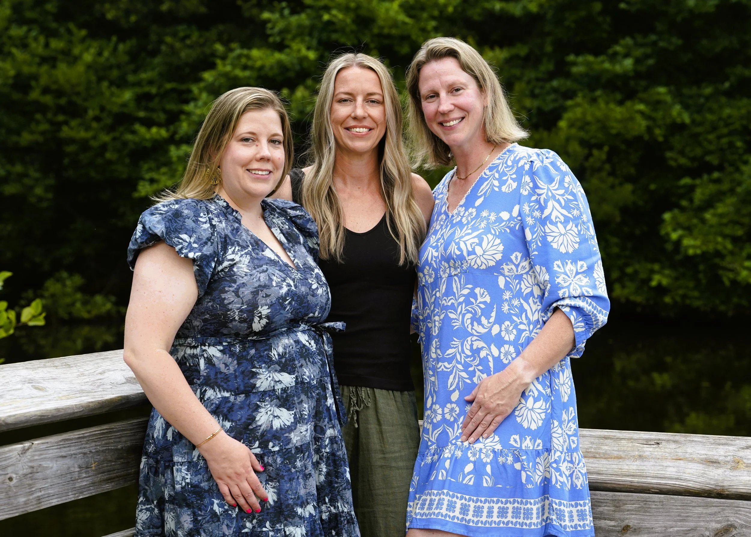 A Raleigh photographer's photo of three sisters for family photos against a background of trees on a wooden dock at Seagroves Park, Apex, North Carolina